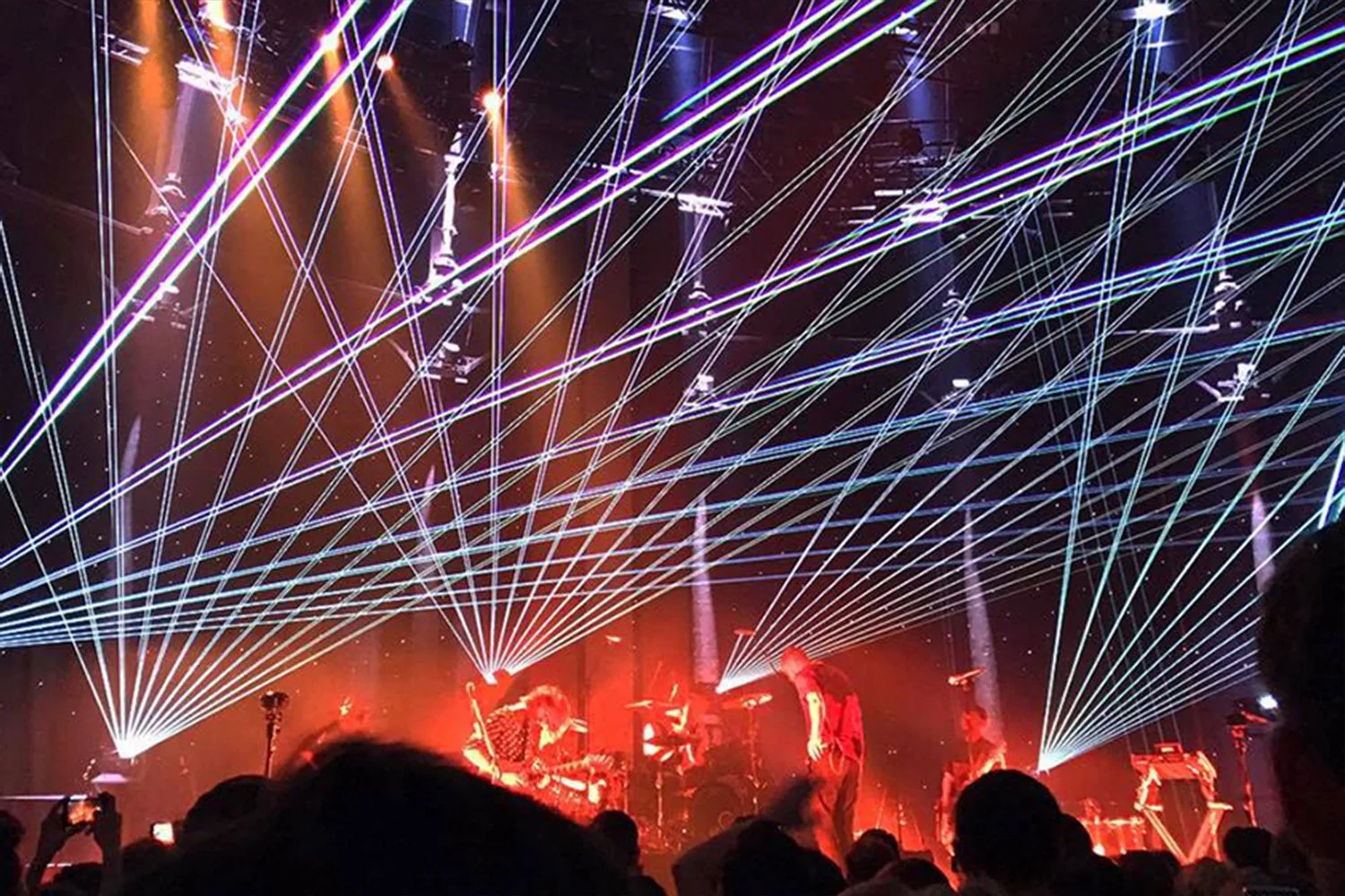 A concert stage with colorful laser light beams and performers.