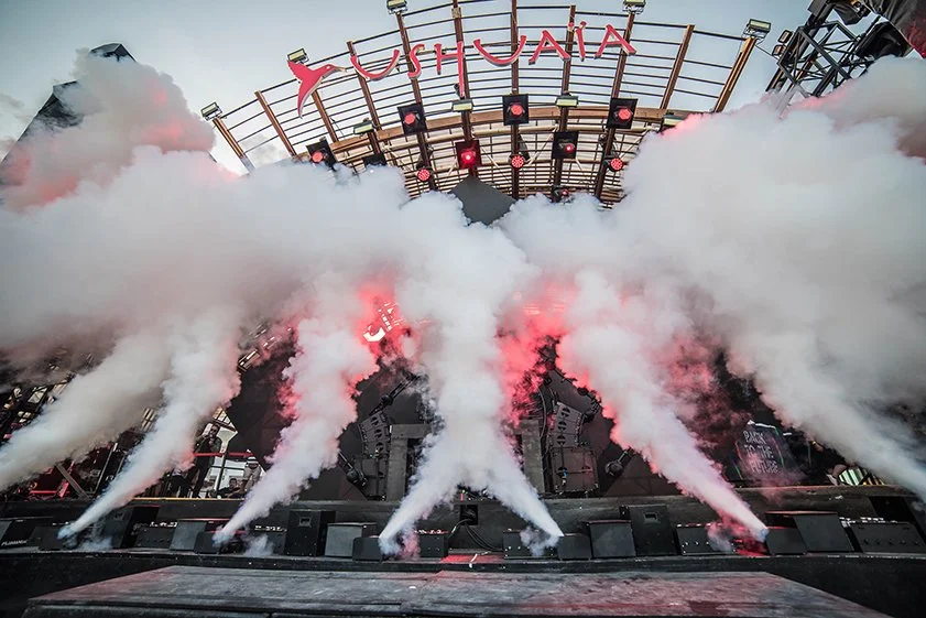 Stage with smoke effects, lighting, and the Ushuaïa sign at an outdoor event or concert venue.