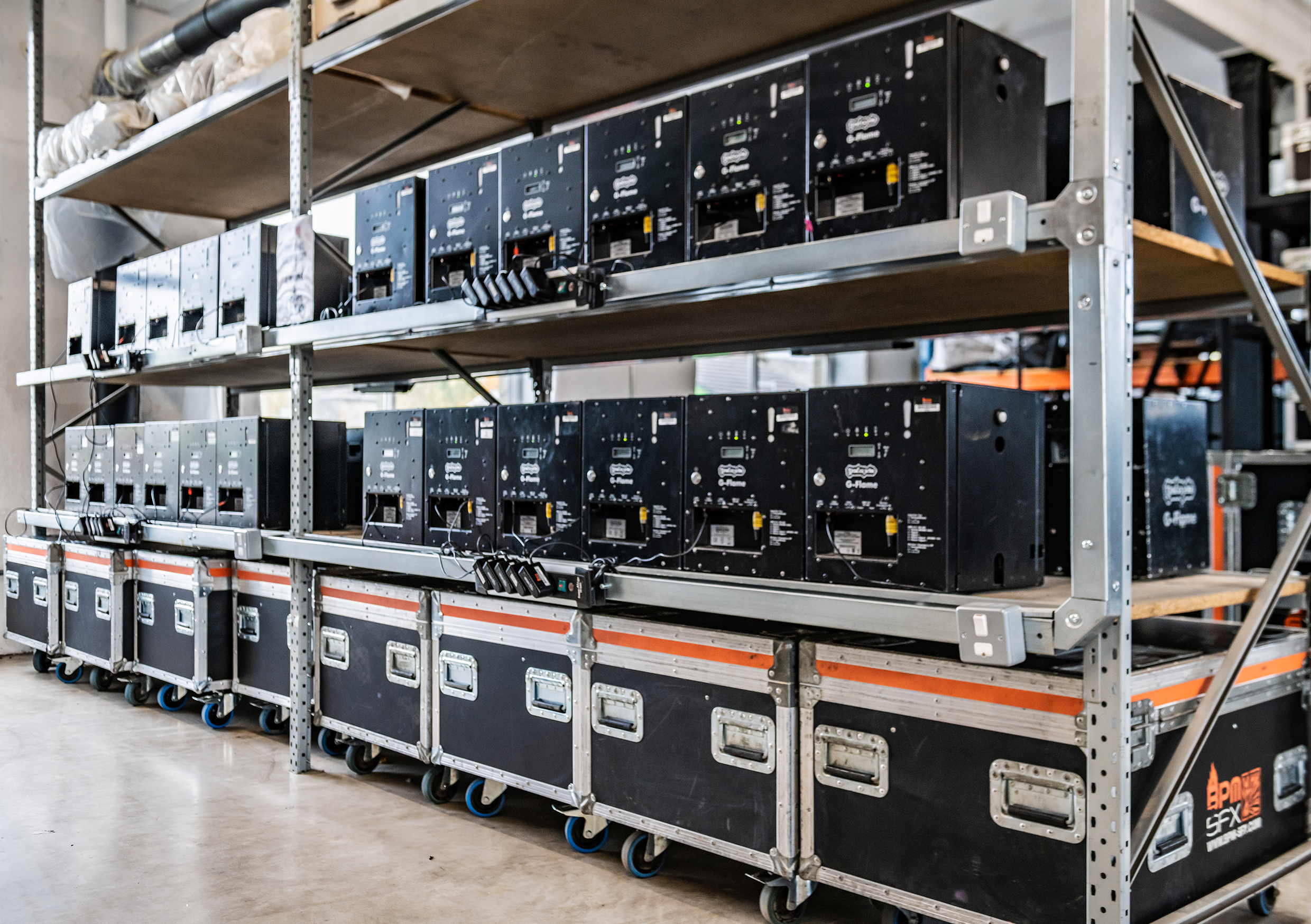 A storage rack on wheels containing black equipment cases in an industrial or warehouse setting.