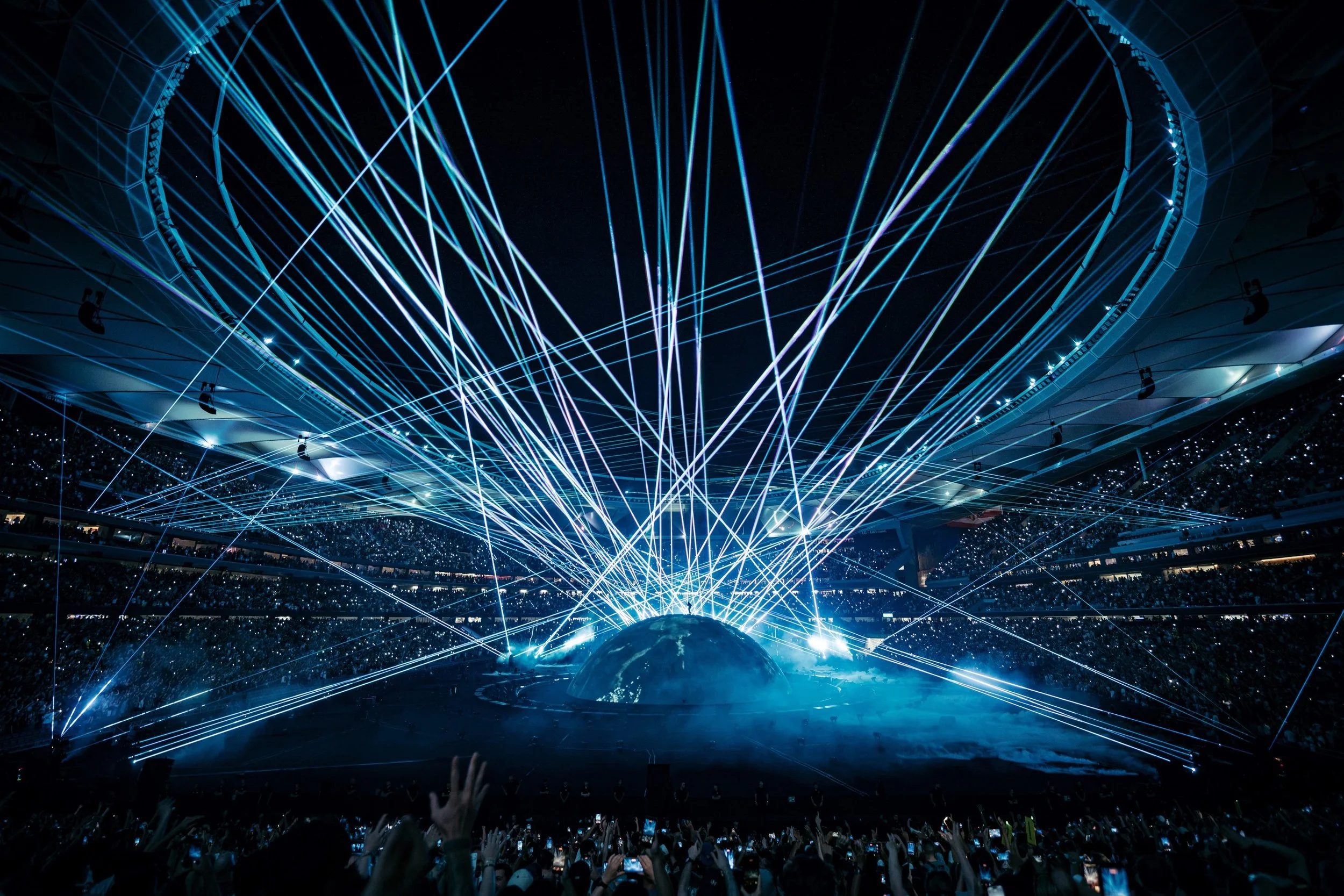 A concert or entertainment event with laser lights and a large audience in a stadium or arena.