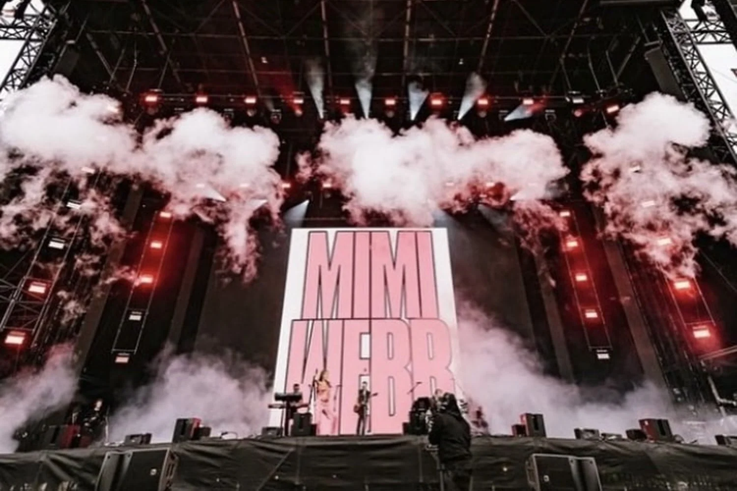 Stage with smoke effects, large screen displaying 'MAMI NBER', and band performing.