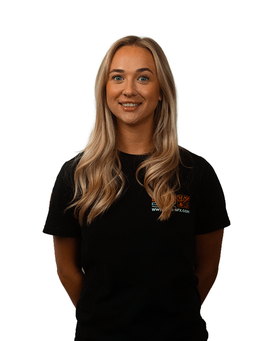 A young woman with long blonde hair, smiling, wearing a black T-shirt with a logo on the chest, standing against a plain background.
