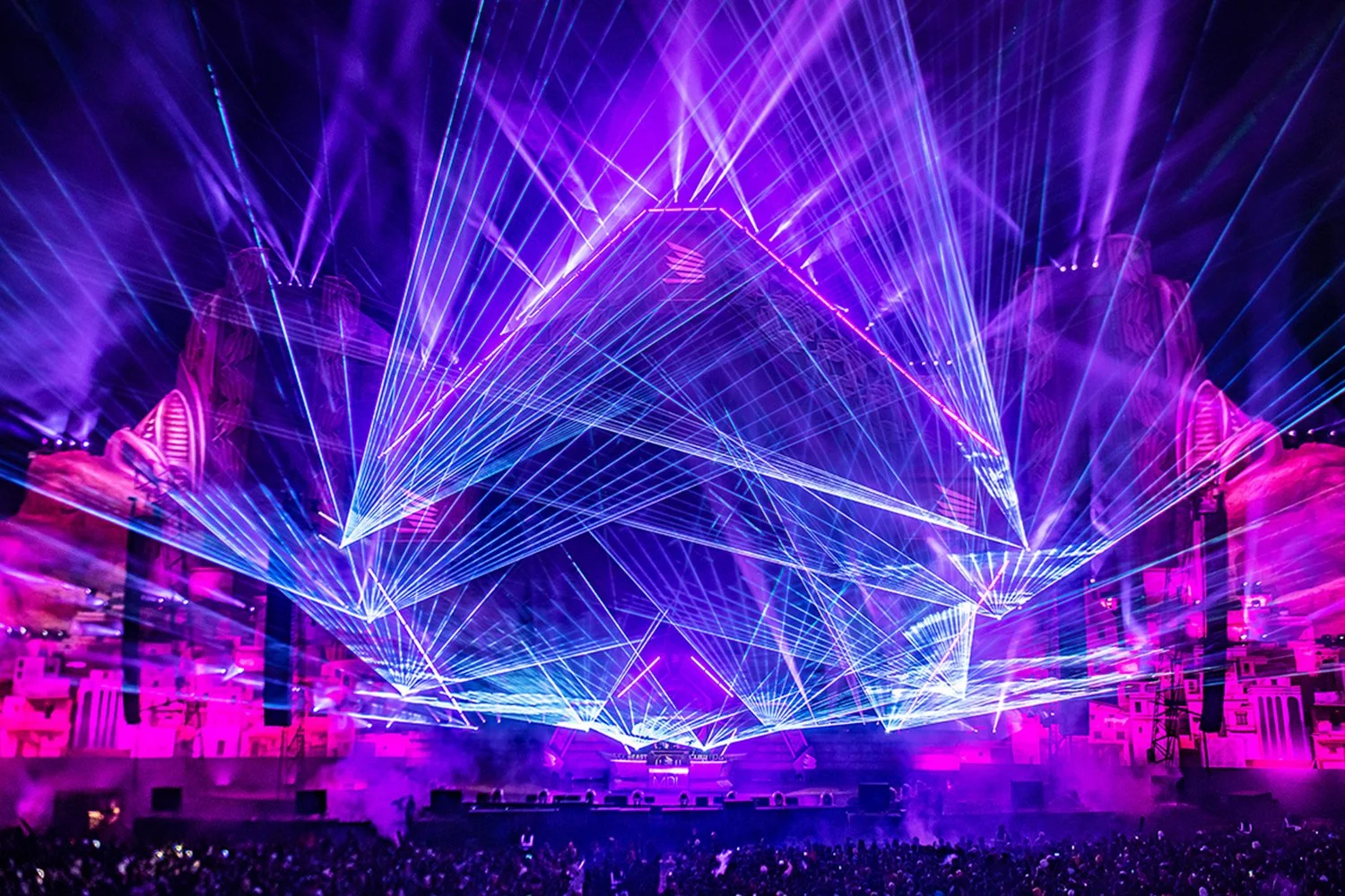 Colorful laser lights at a music concert or festival with a large crowd.