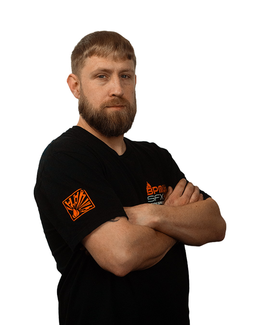 A man with a beard and short hair standing with arms crossed, wearing a black t-shirt with orange and white logos and text. The background is transparent.