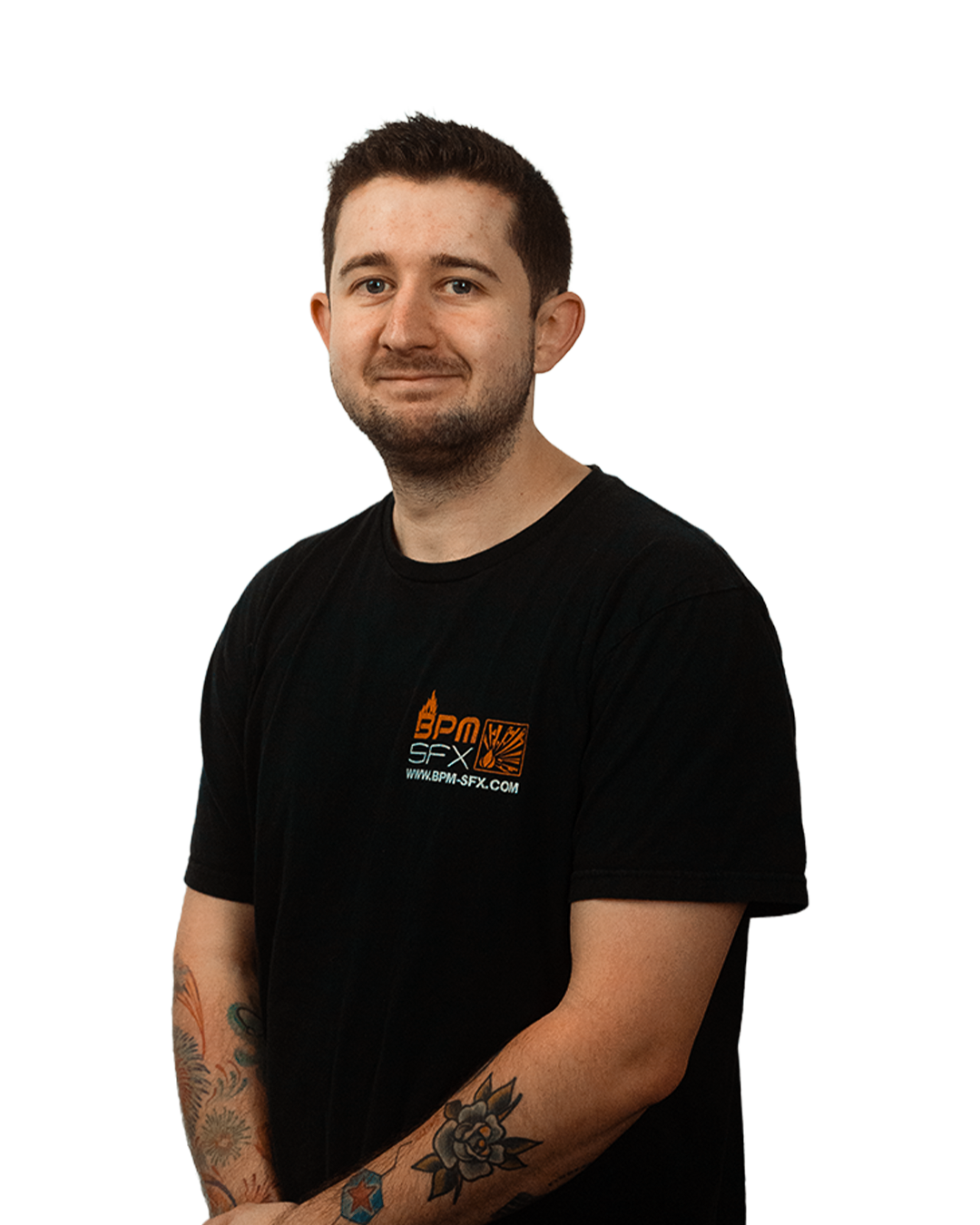 A young man with short dark hair and a light beard, wearing a black T-shirt with an orange and white logo and text, standing with arms crossed and smiling slightly.