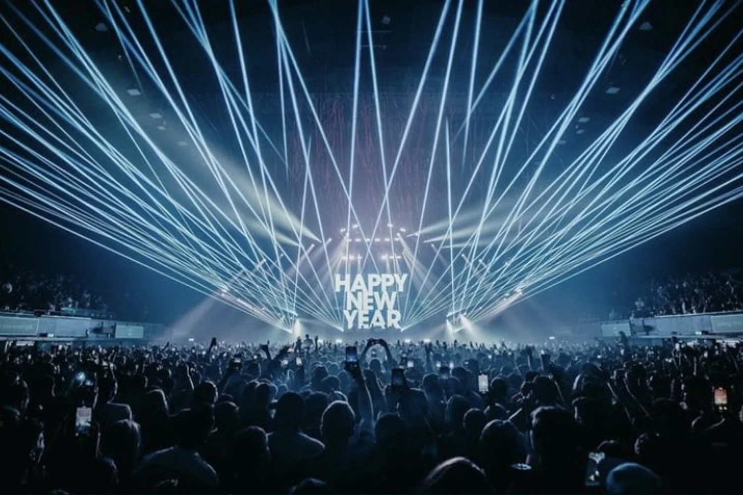Crowd at a concert with laser light show; large screen displays 'HAPPY NEW YEAR'