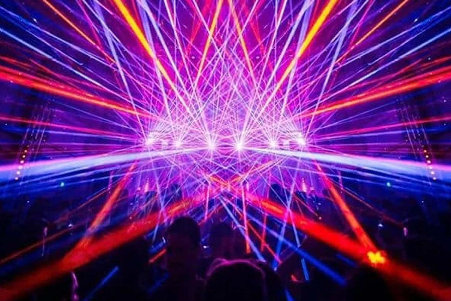 Colorful laser lights creating a vibrant display with people watching in the foreground.