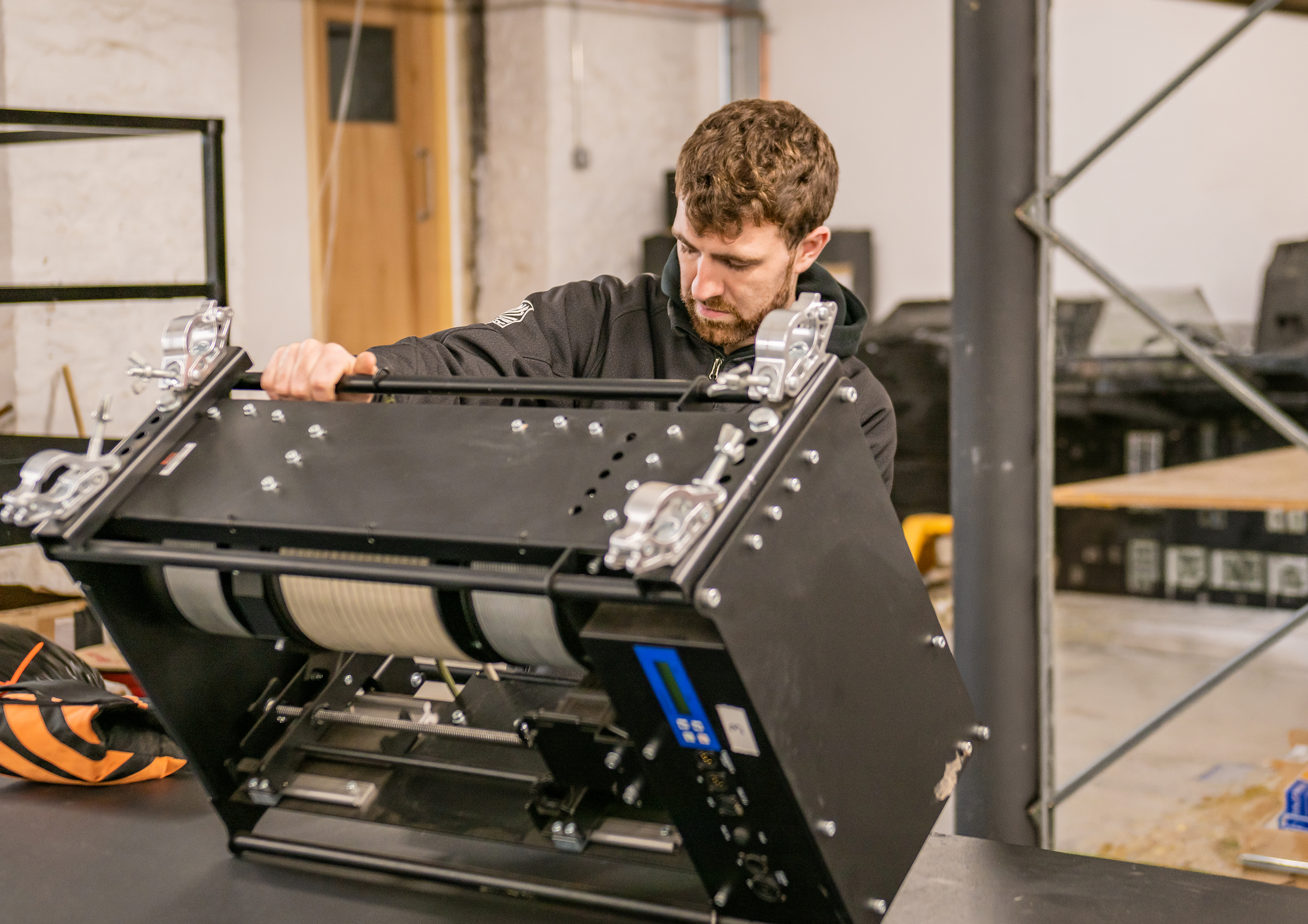 A man working on a piece of machinery or equipment in a workshop or industrial setting.