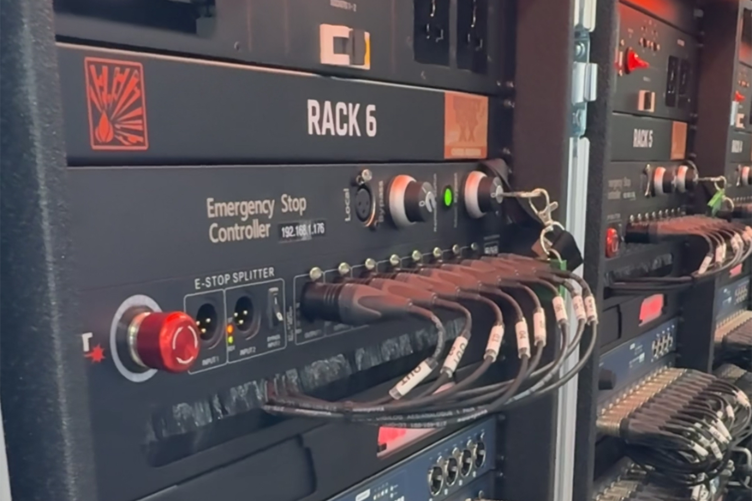 Electrical control panel with labeled rack 6, emergency stop controller, and multiple connected cables.
