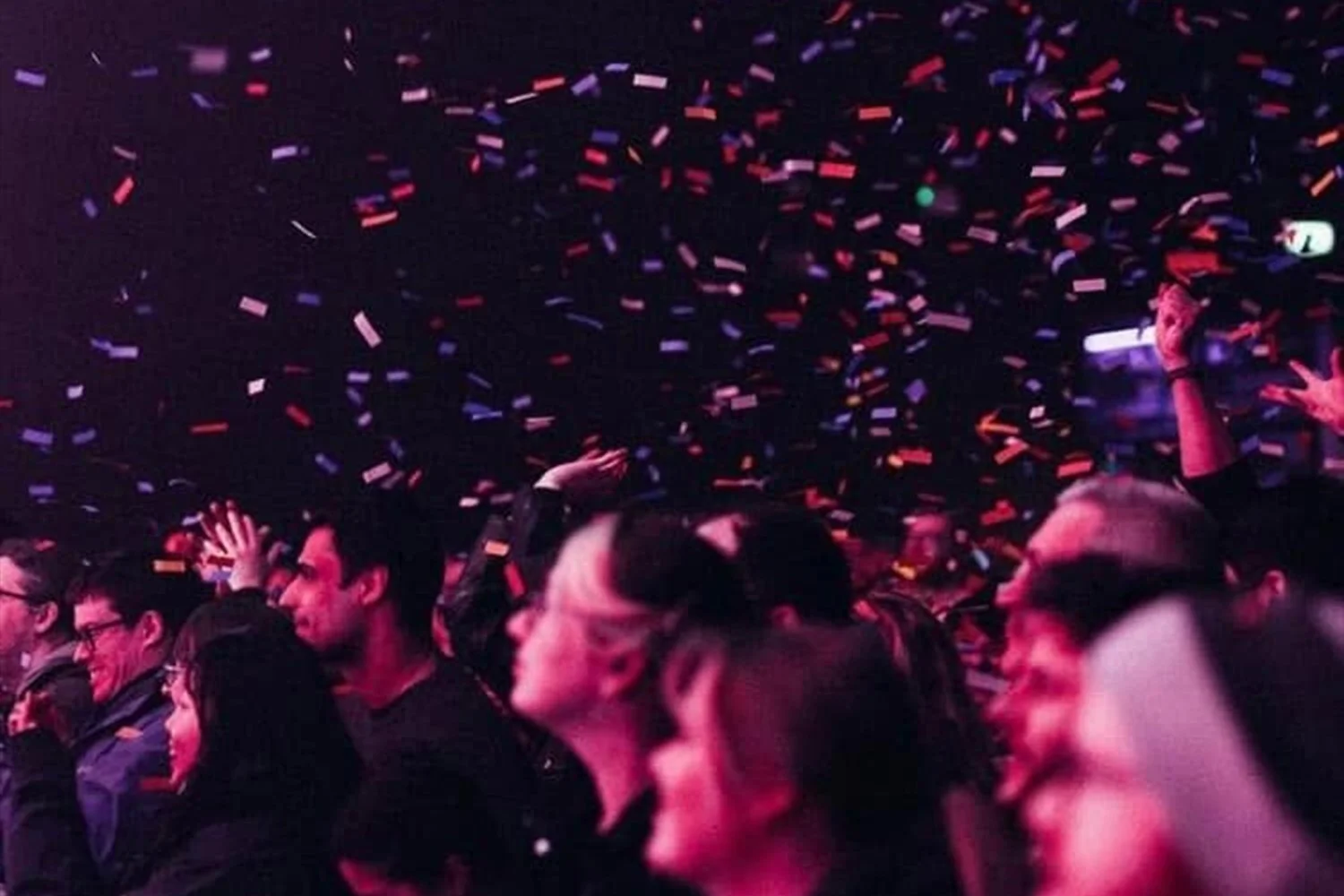 People celebrating at a party with colorful confetti falling from the ceiling.
