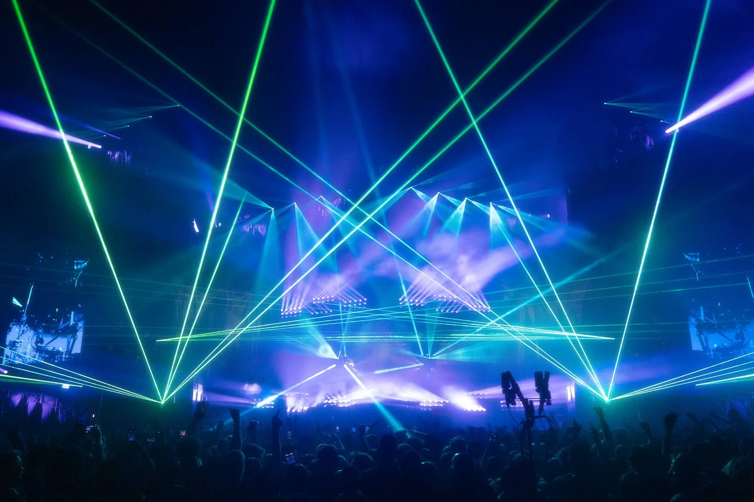Concert or music festival with colorful laser lights and an audience.