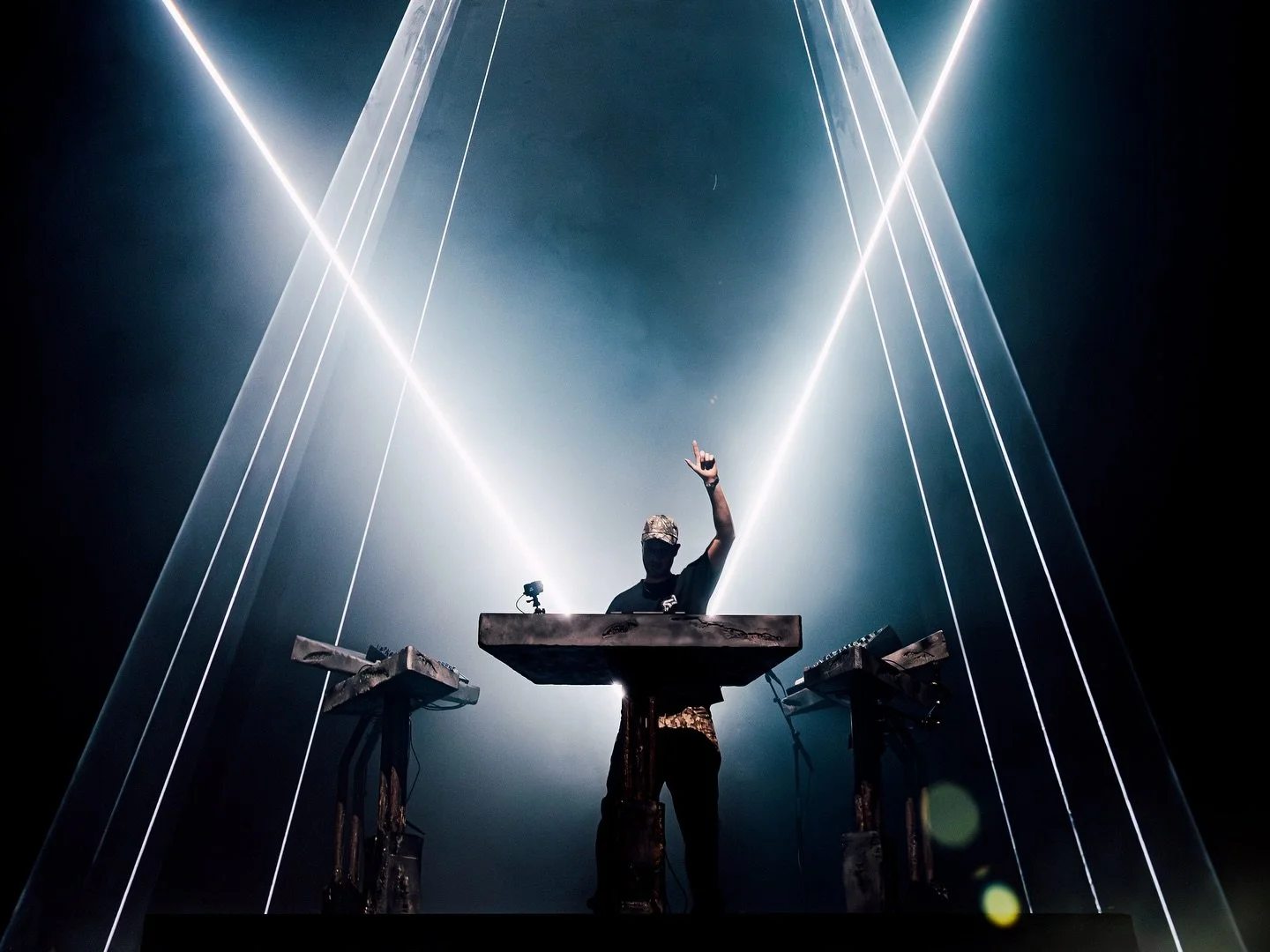 A DJ performing on stage with laser lights creating a dramatic atmosphere.