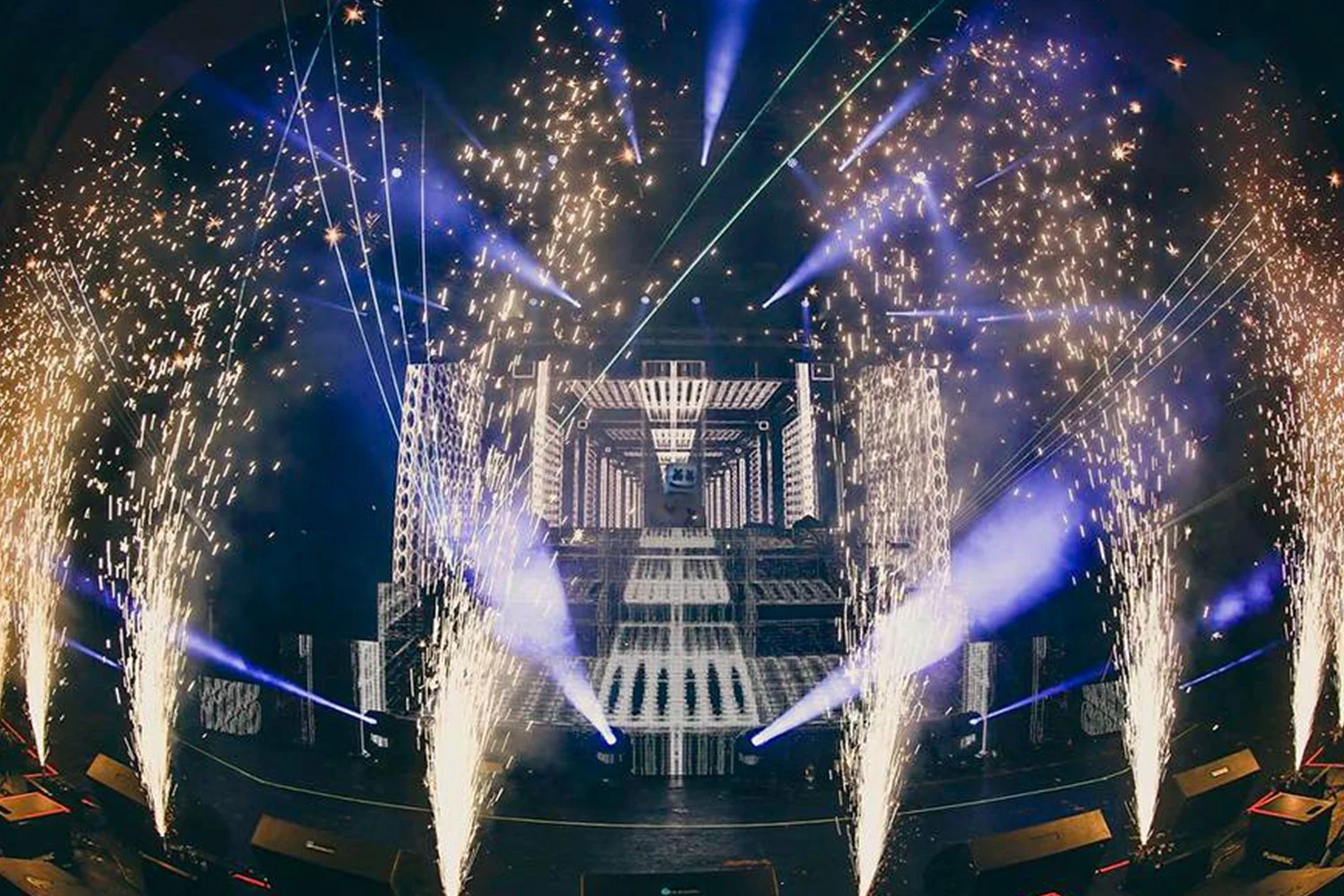 A concert stage with pyrotechnics, colorful lights, and an intricate LED screen display.