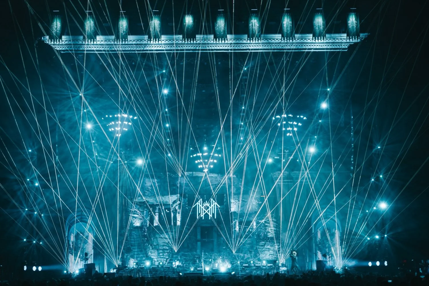 A concert stage illuminated with blue lights and laser beams.