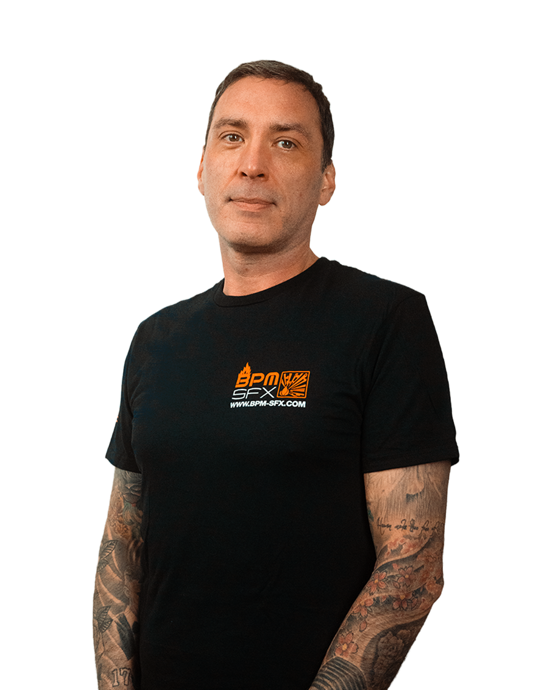 A man with short dark hair and tattoos on both arms wearing a black t-shirt with an orange and white logo, standing against a background with glitch-like streaks.