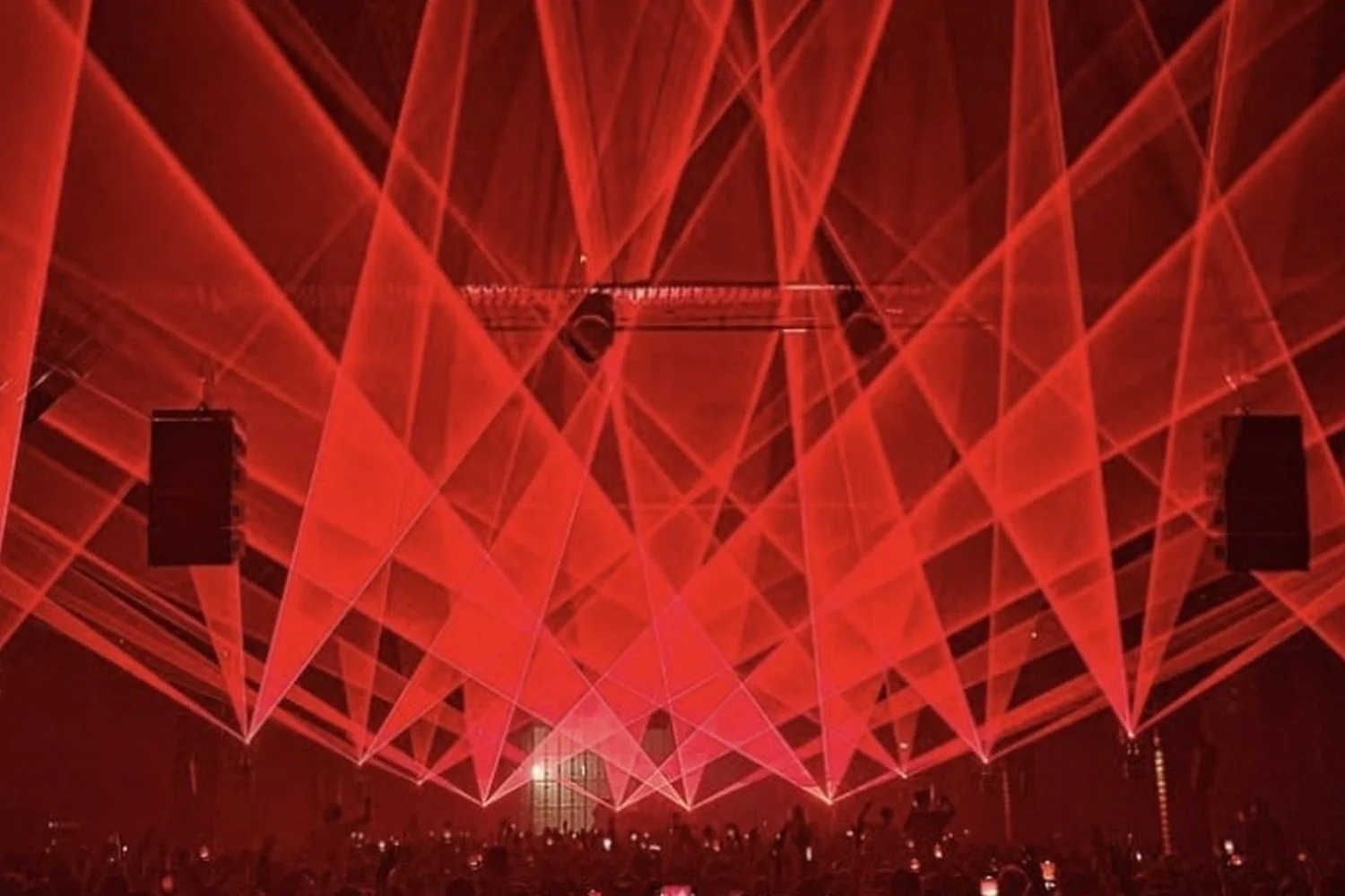 Red laser lights crossing over a crowd during a concert or event.