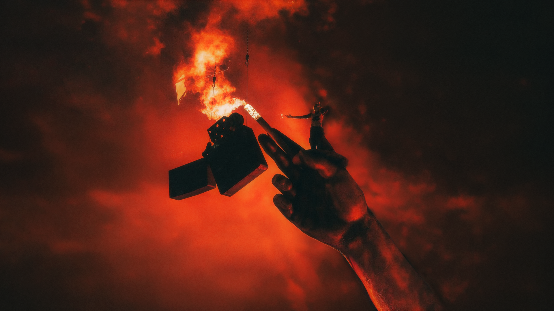 A person holding a lit flare in one hand and a small doll in the other, against a fiery, smoky background.