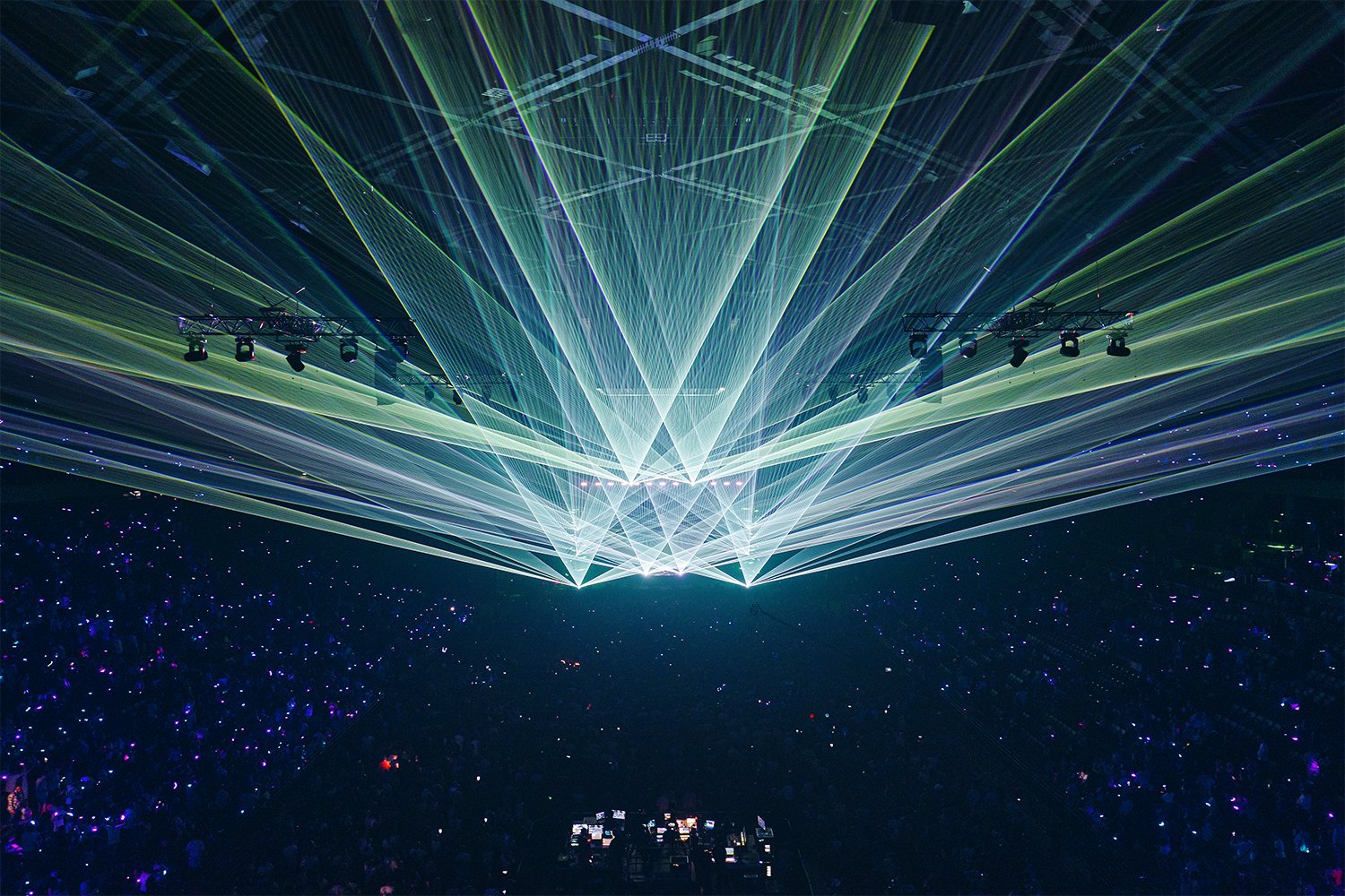 A concert or event with laser lights and a large crowd in a dark venue.