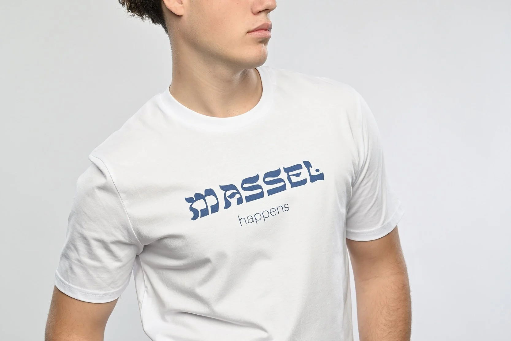Ein junger Mann trägt ein weisses T-Shirt der Marke SHALOM.BERLIN mit blauem Aufdruck "MASSEL happens"