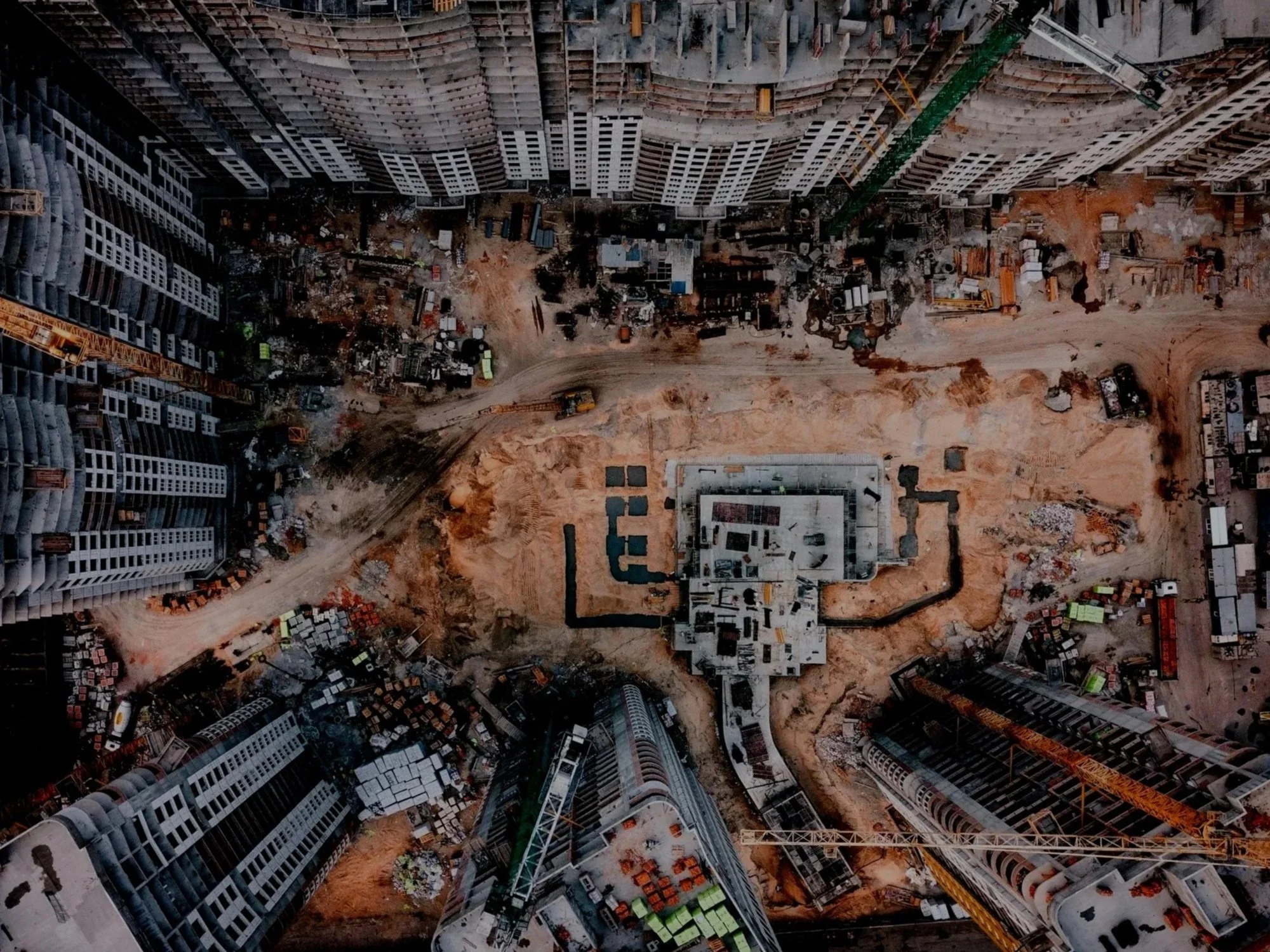 Workers wearing yellow helmets and blue uniforms climbing an orange ladder against a clear blue sky.