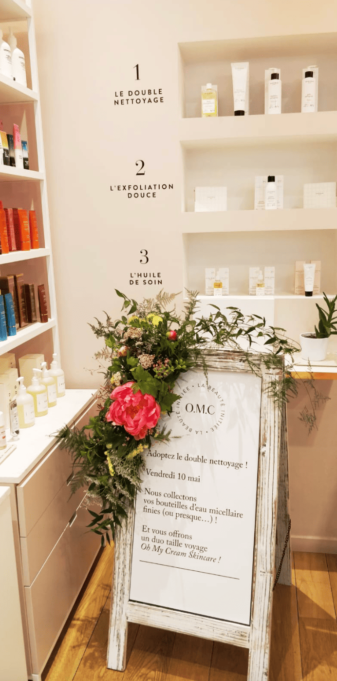 Une affiche de promotion d'un soin de soin de la peau avec un arrangement floral à côté, dans une boutique de produits cosmétiques.