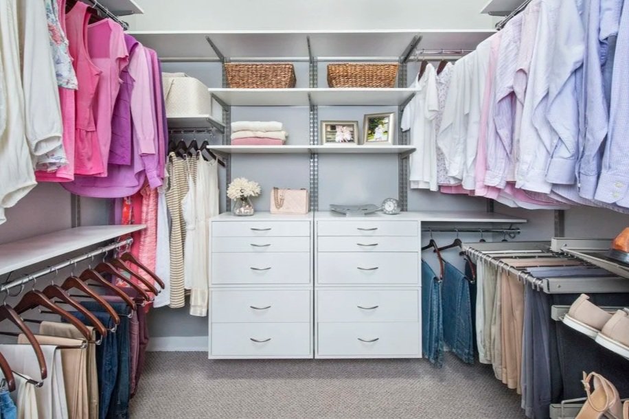 Organized walk-in closet with drawers, shelves, and hanging racks for 2 people with her clothes on the left and his clothes on the right