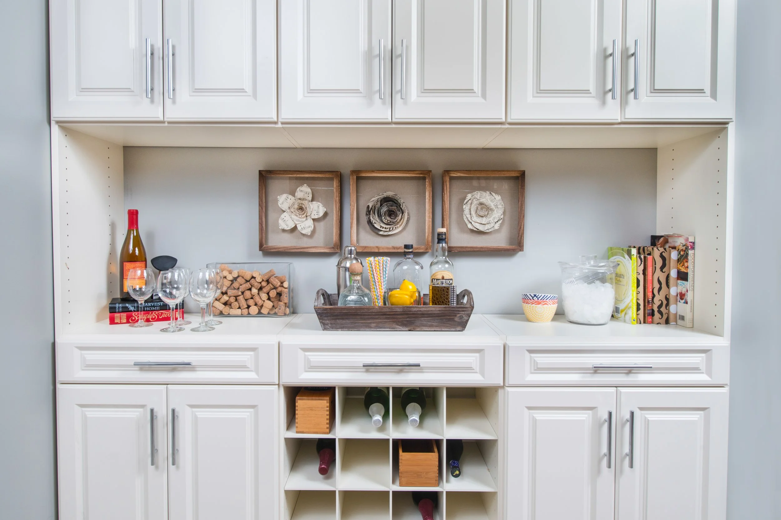 Custom cabinetry in laundry room with shoe shelves, hanging rods, cabinets, drawers and a storage island, shown in an ivory finish with chrome hardware