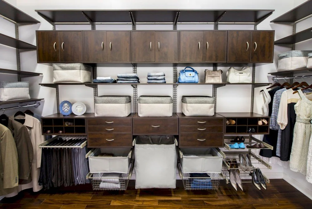 Organized walk-in closet featuring many adjustable components including shelves, drawers, cabinets, baskets, hampers, and more so clothing, shoes, handbags, and accessories are all easily accessible