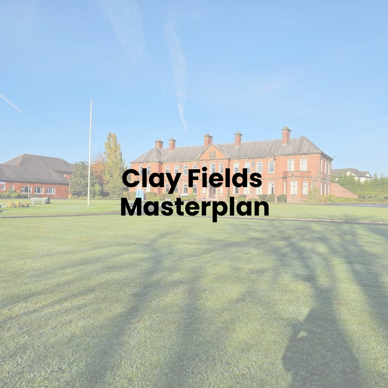A large red brick building with a lawn and trees in front, under a bright blue sky.