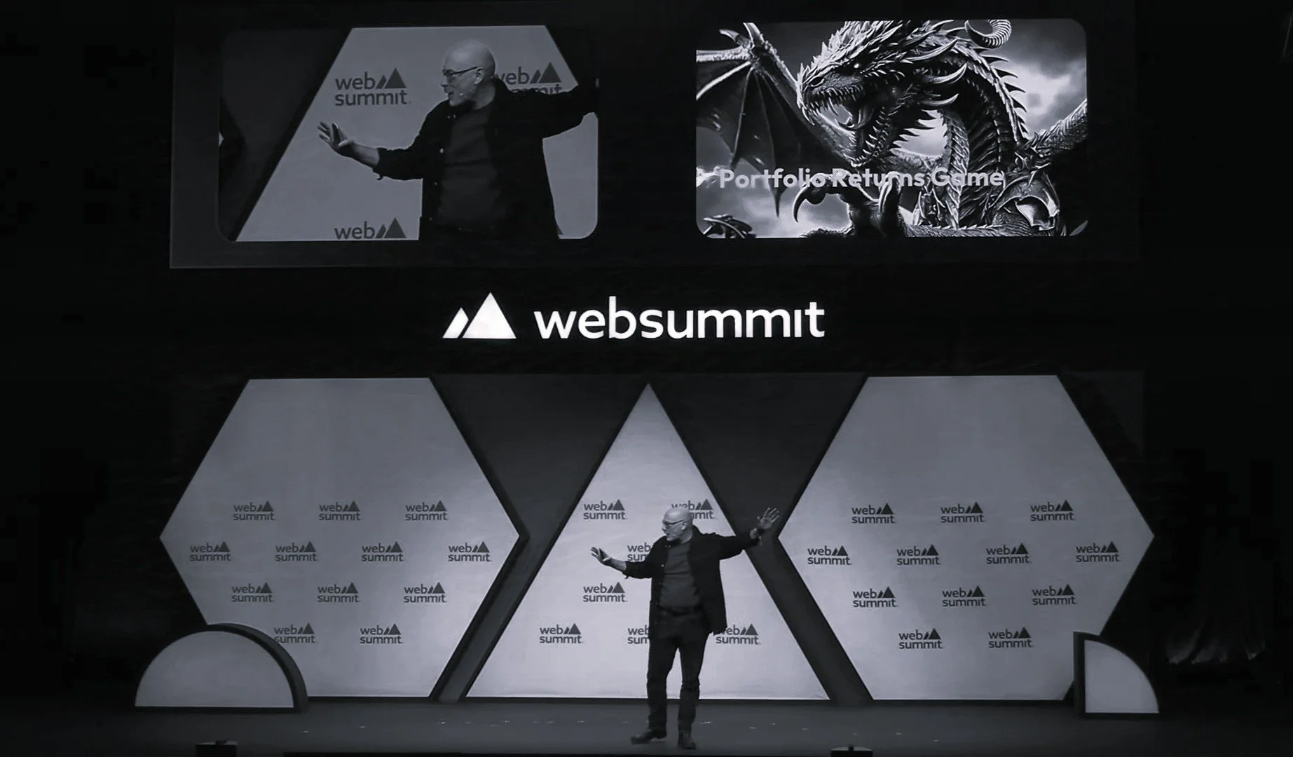 Mike Sigal on stage at Web Summit giving a presentation, with large screens behind him displaying the Web Summit logo, an image of a dragon, and a slide titled 'Portfolio Returns Game.'