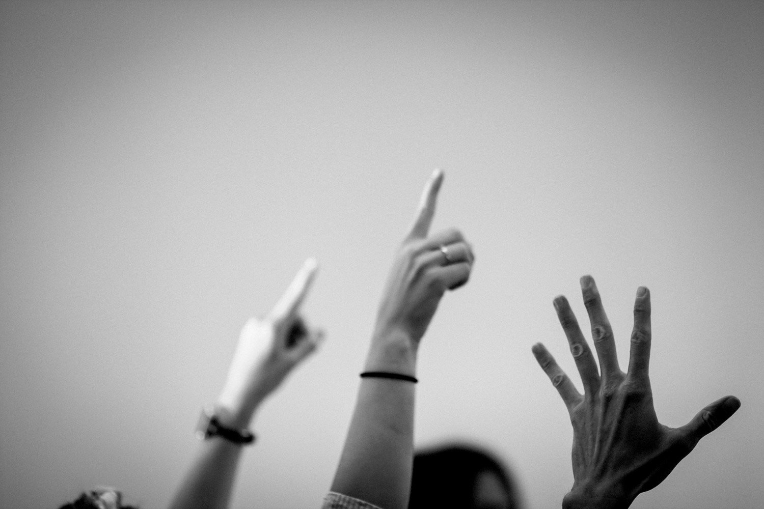 Multiple hands raised with some gesturing with fingers, black and white photo.