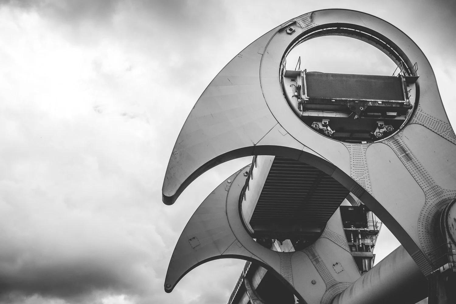 Black and white photo of a modern architectural structure with curved forms and circular openings, possibly part of a bridge or building design.