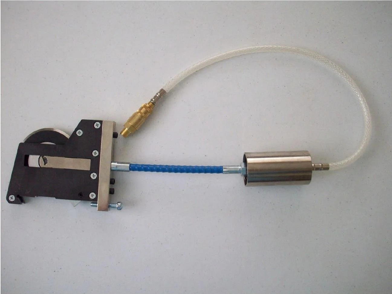 A mechanical device with a black base, metal components, and attached tubing with brass fittings.