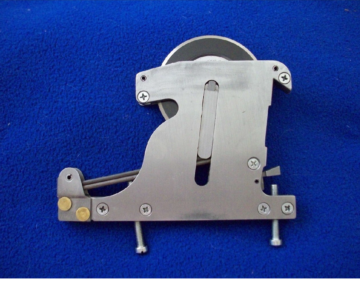 A metal mechanical device with screws, springs, and sliders placed on a blue fabric background.