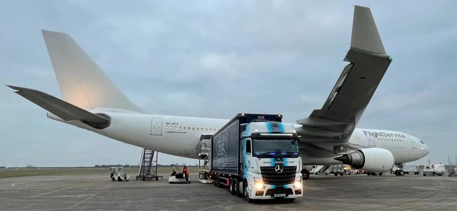 A large commercial airplane on the tarmac with a truck in front of it, preparing for boarding or cargo loading.