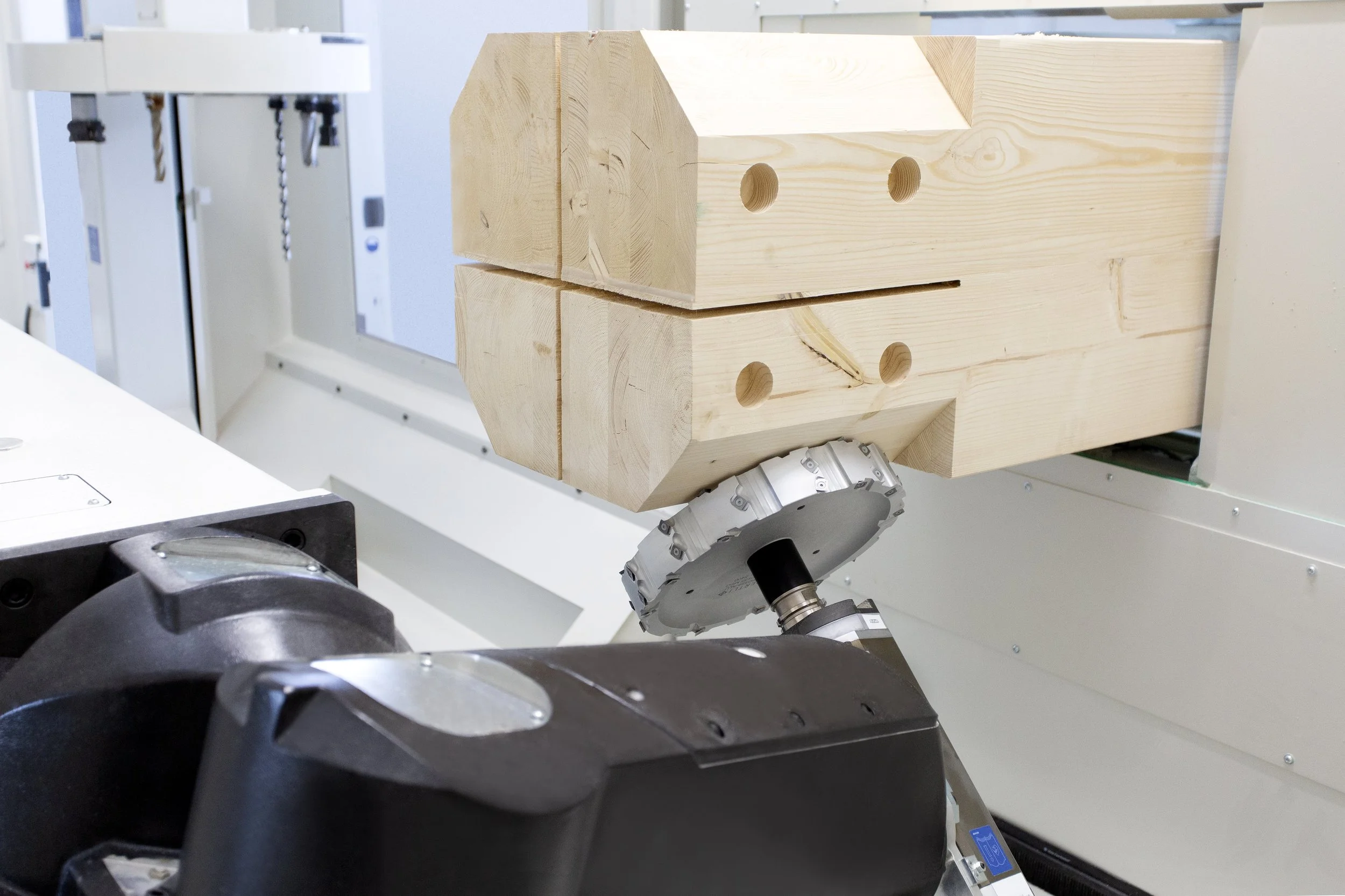 Un robot industriel manipule un bloc de bois dans une usine.