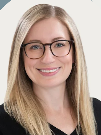 Happy customer, Dr. Jackie Kantor, poses for a portrait. She has blonde hair, glasses, and is wearing a black shirt. 