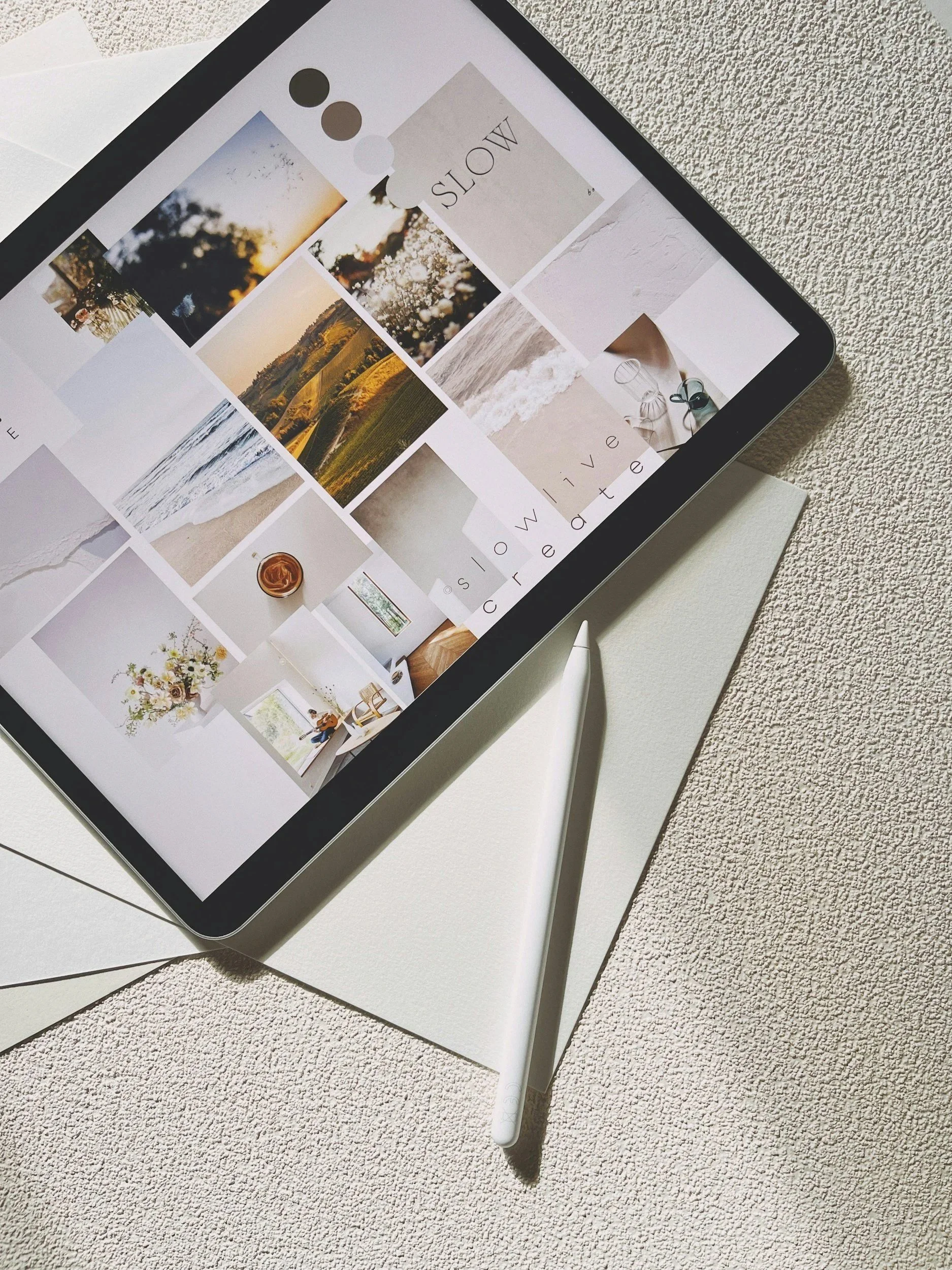 An iPad with a stylus on a white desk, displaying a photo collage and text, with papers nearby.