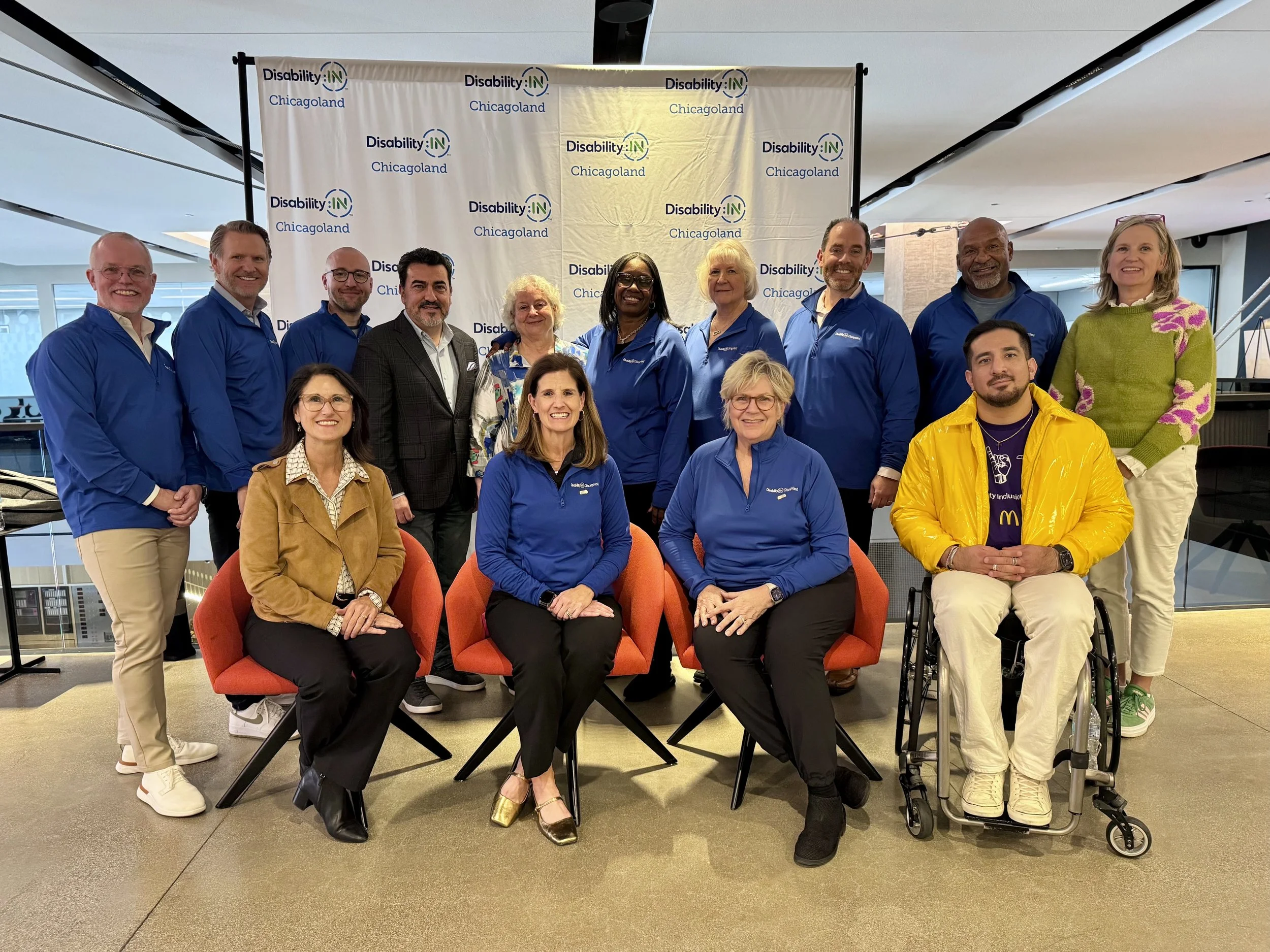 Group of people standing and sitting in front of a step and repeat that reads "Disability:IN Chicagoland"