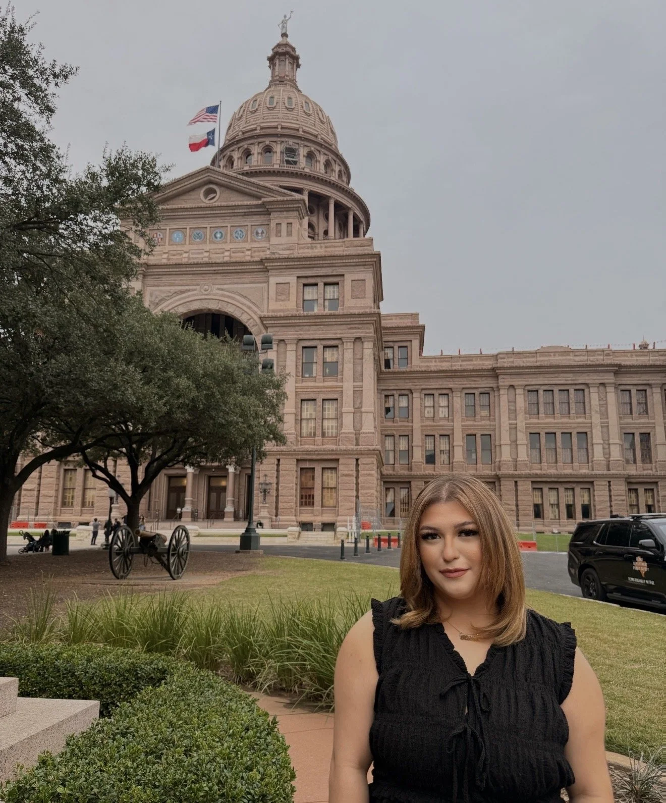 A woman with brown, wavy hair standing next to a gray wall with a logo that reads 'The Mendez Law Group.'
