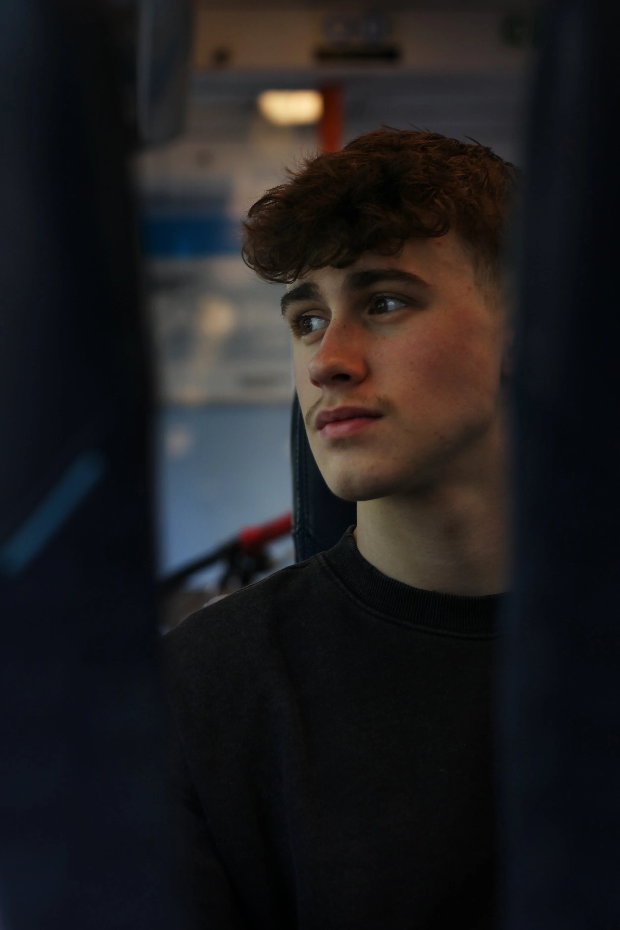 A young man looking wistfully out of a train window in Surrey. Photographer: Blake Charles.