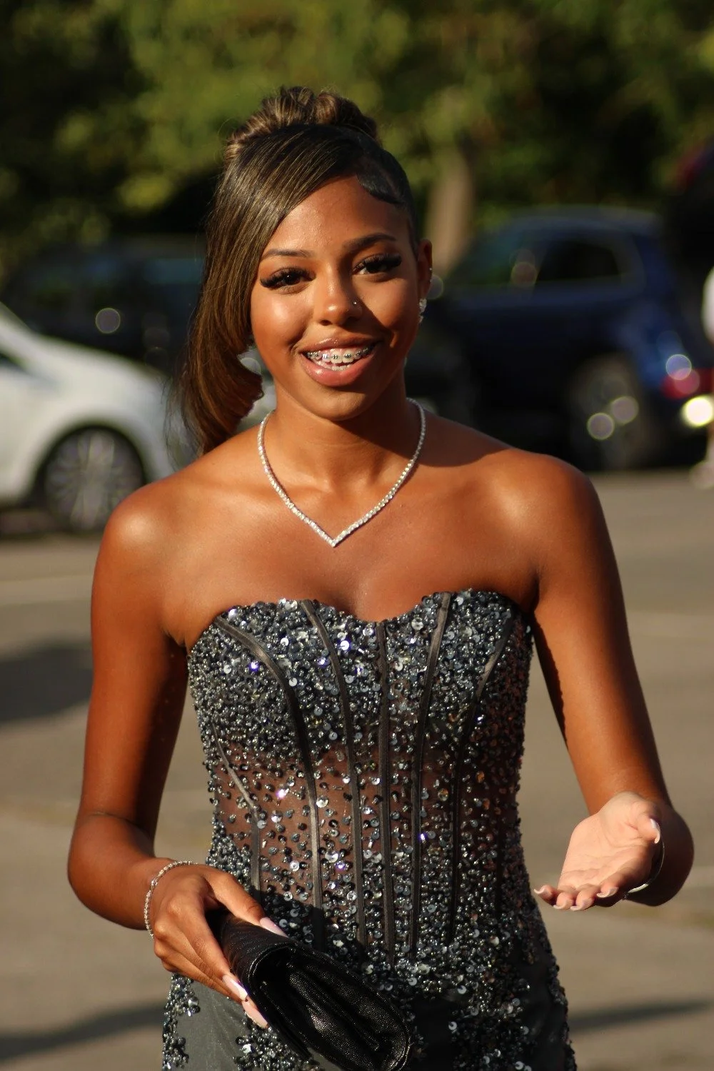 A young woman in a sparkly, strapless evening gown smiling outdoors. Prom in Pyrford, Woking, Surrey. Photographer: Blake Charles.
