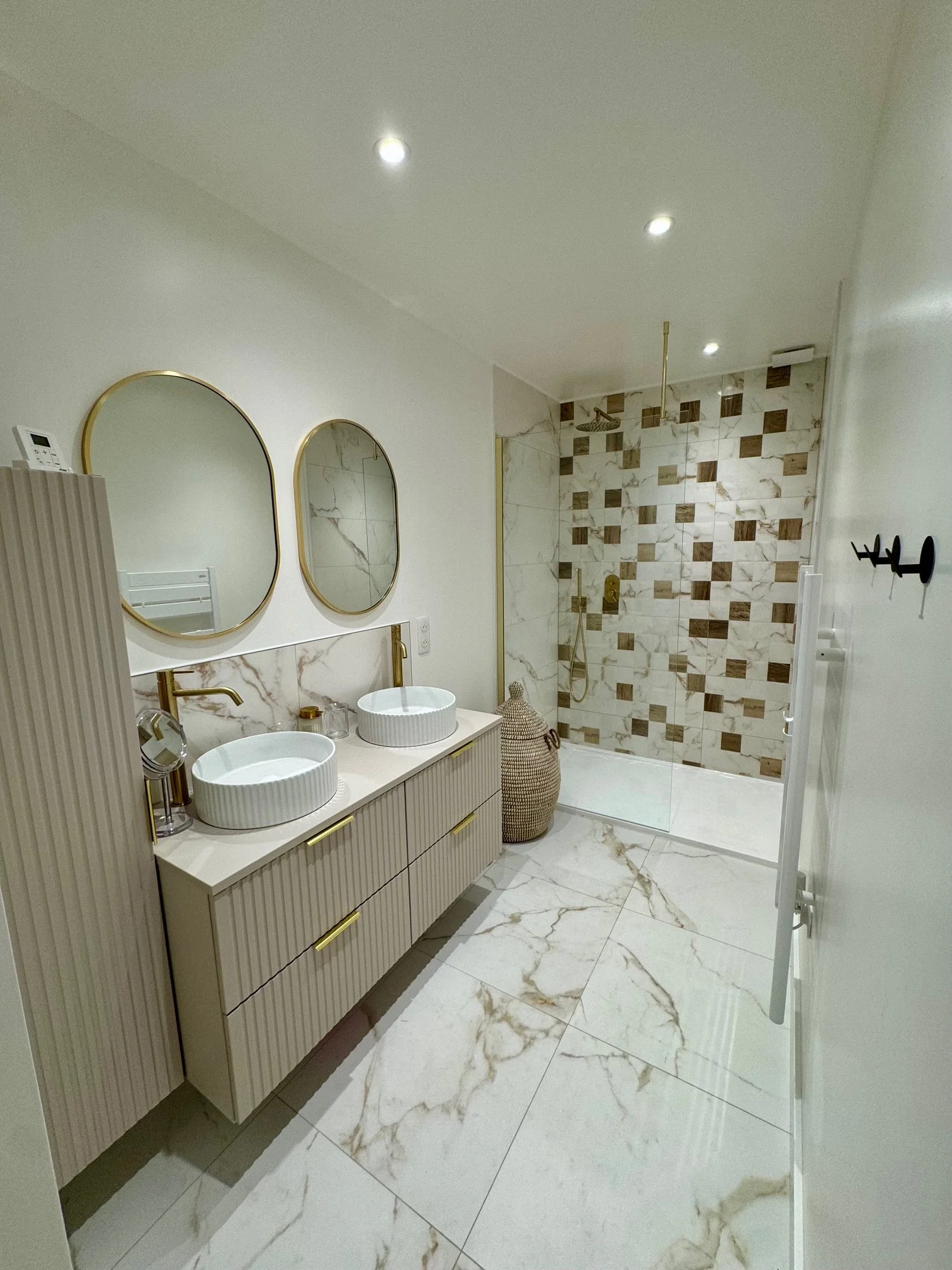 Salle de bain élégante avec meuble lavabo double vasque, sols en marbre et décoration en bois et or.