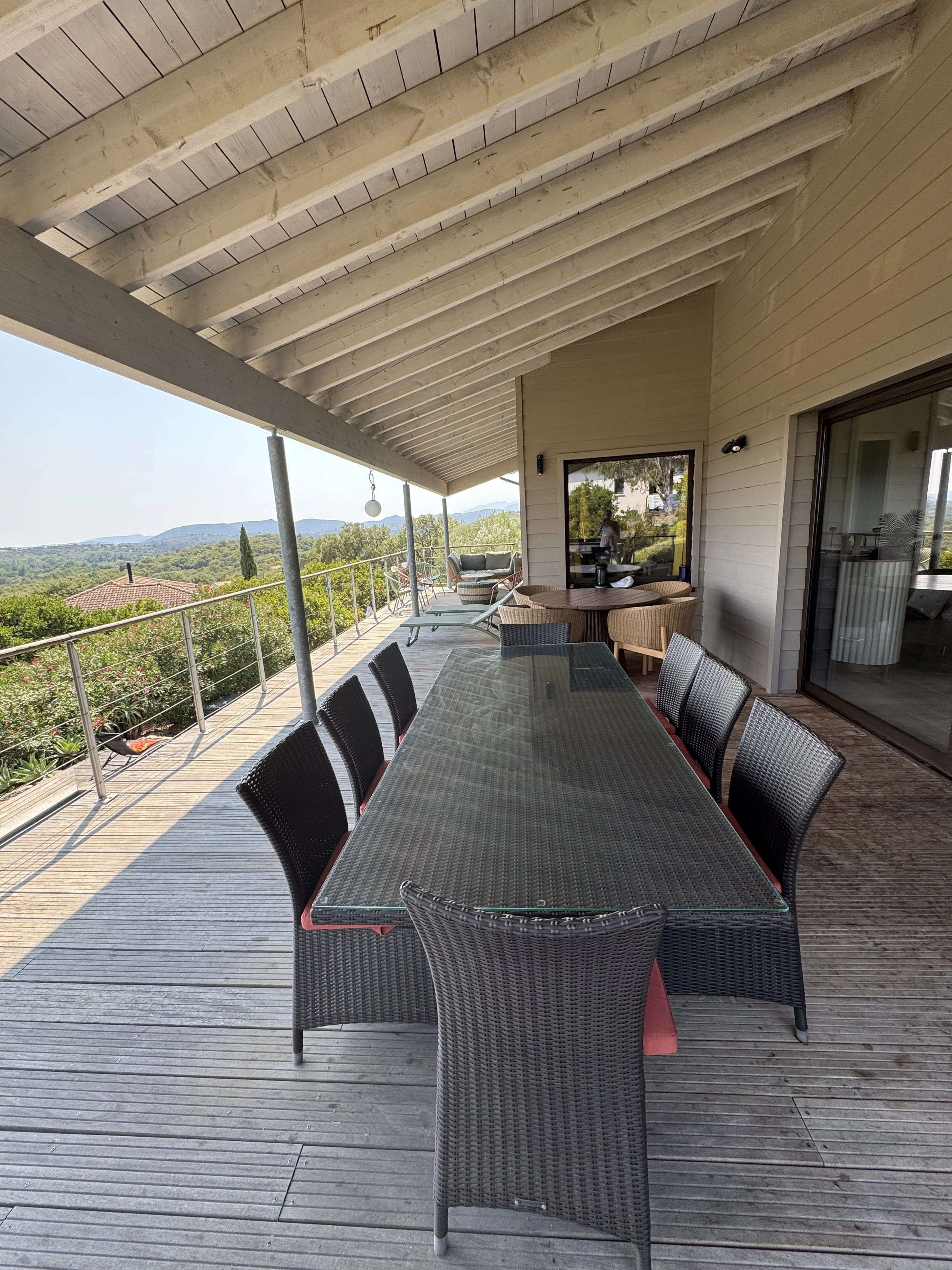 Terrasse couverte , avec une table 10 personnes en résine tressée et une table 6 personnes en bois.