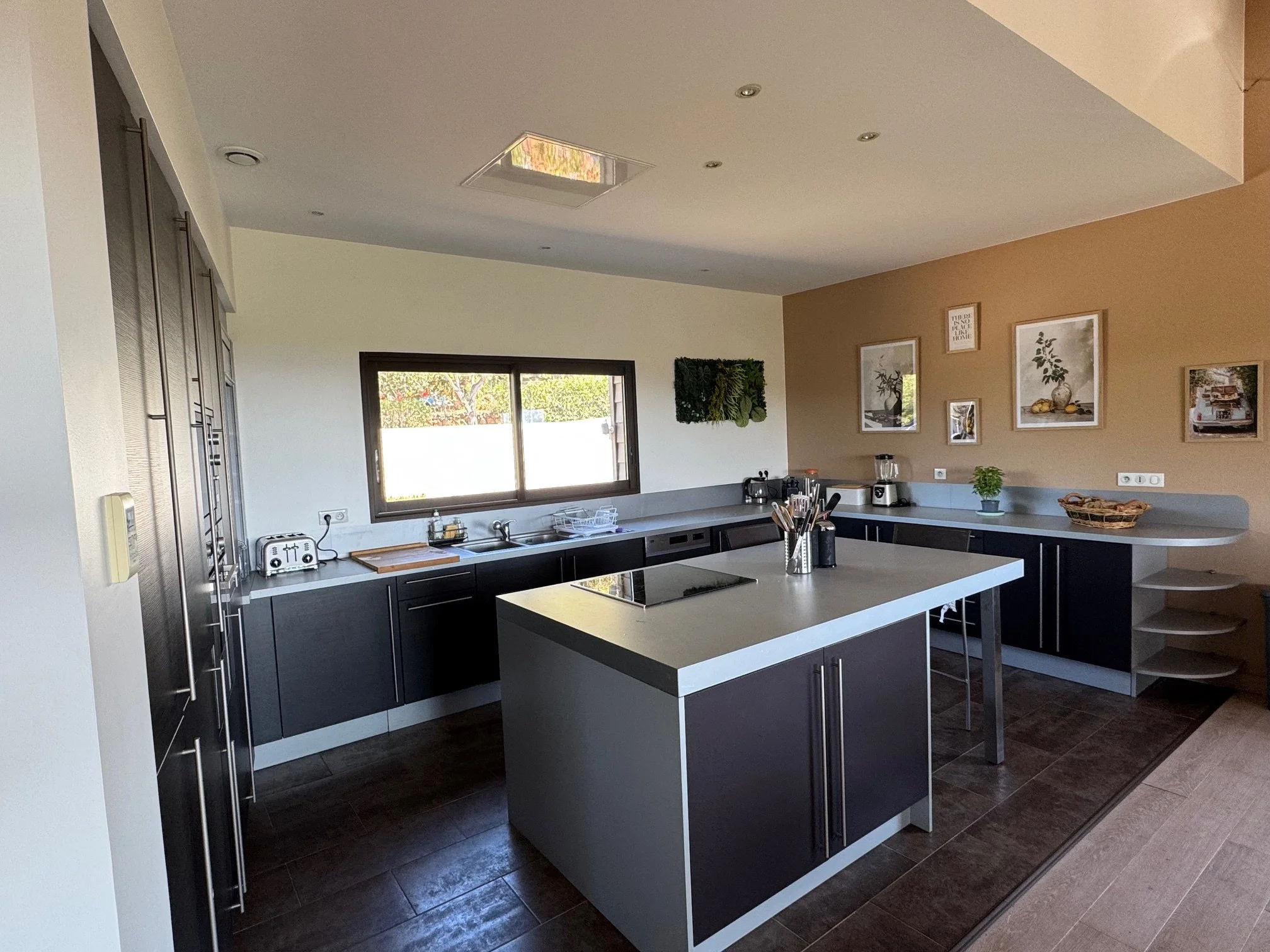 Cuisine moderne équipée avec îlot central, réfrigérateur combiné, four, micro-ondes et lave vaisselle.