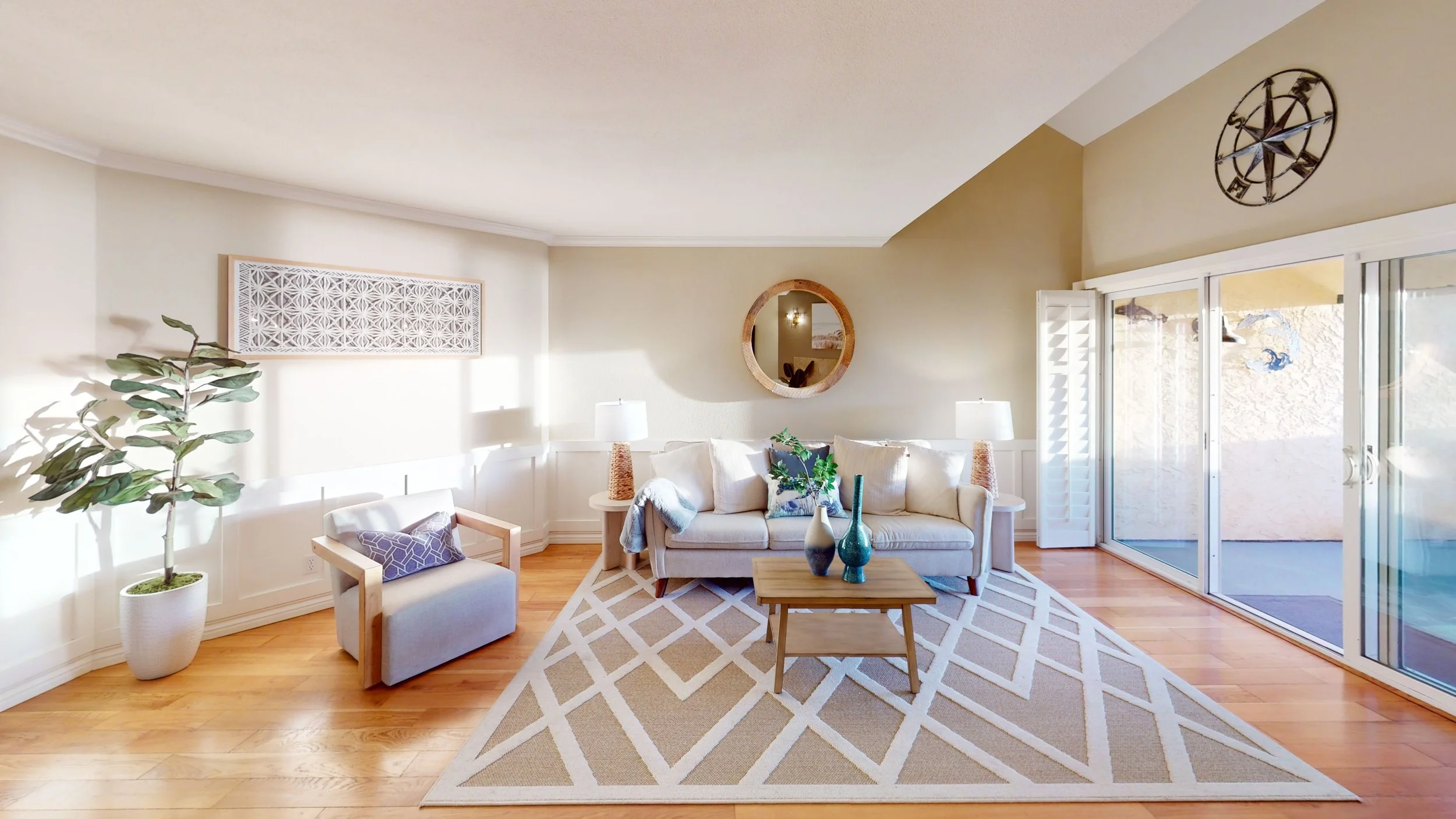Living room with white sofa, small armchair, coffee table with decorative vases, area rug, built-in side tables with lamps, wall decor, sliding glass doors, and a large wall clock.