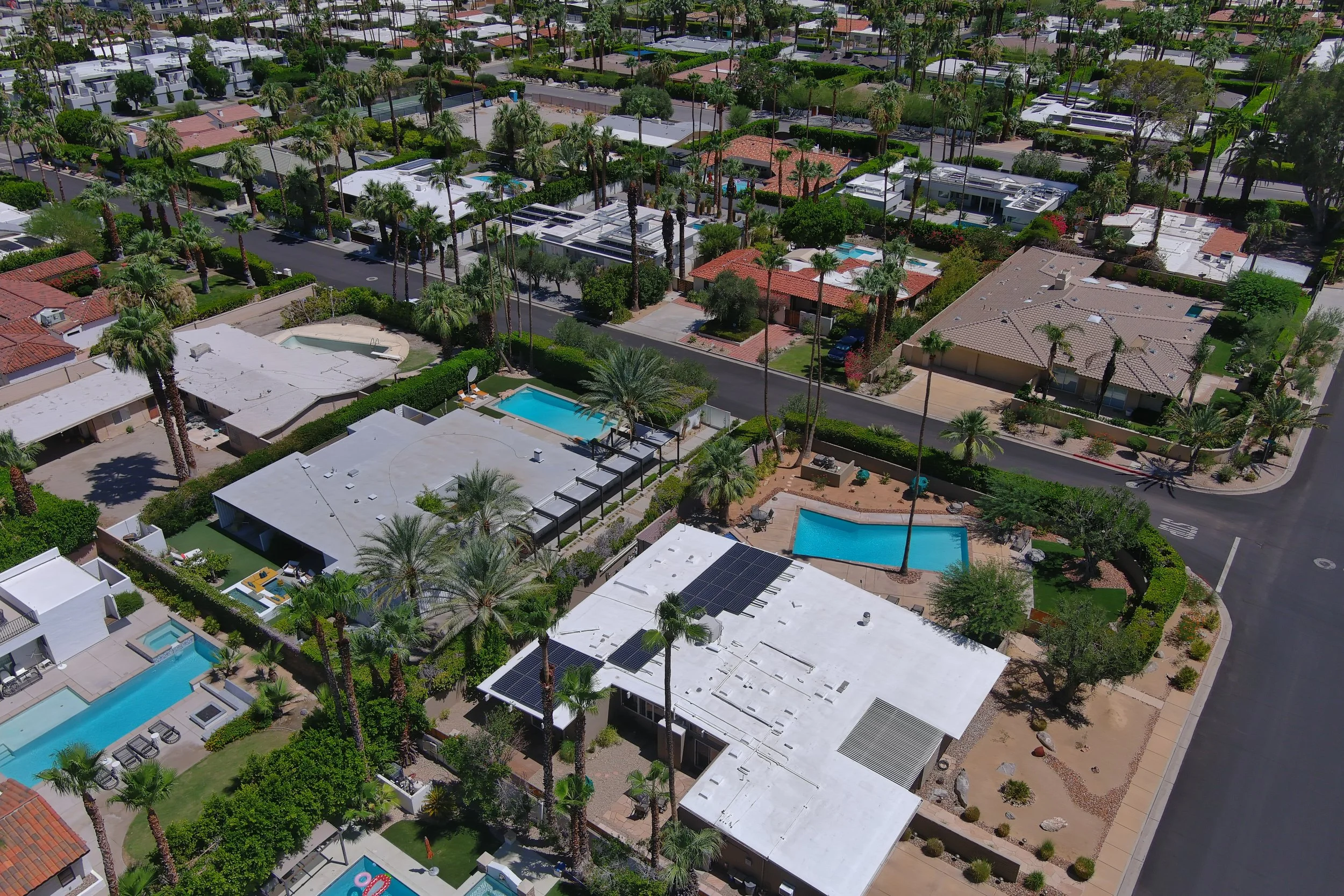 Aerial view of a residential neighborhood with houses, palm trees, and swimming pools.