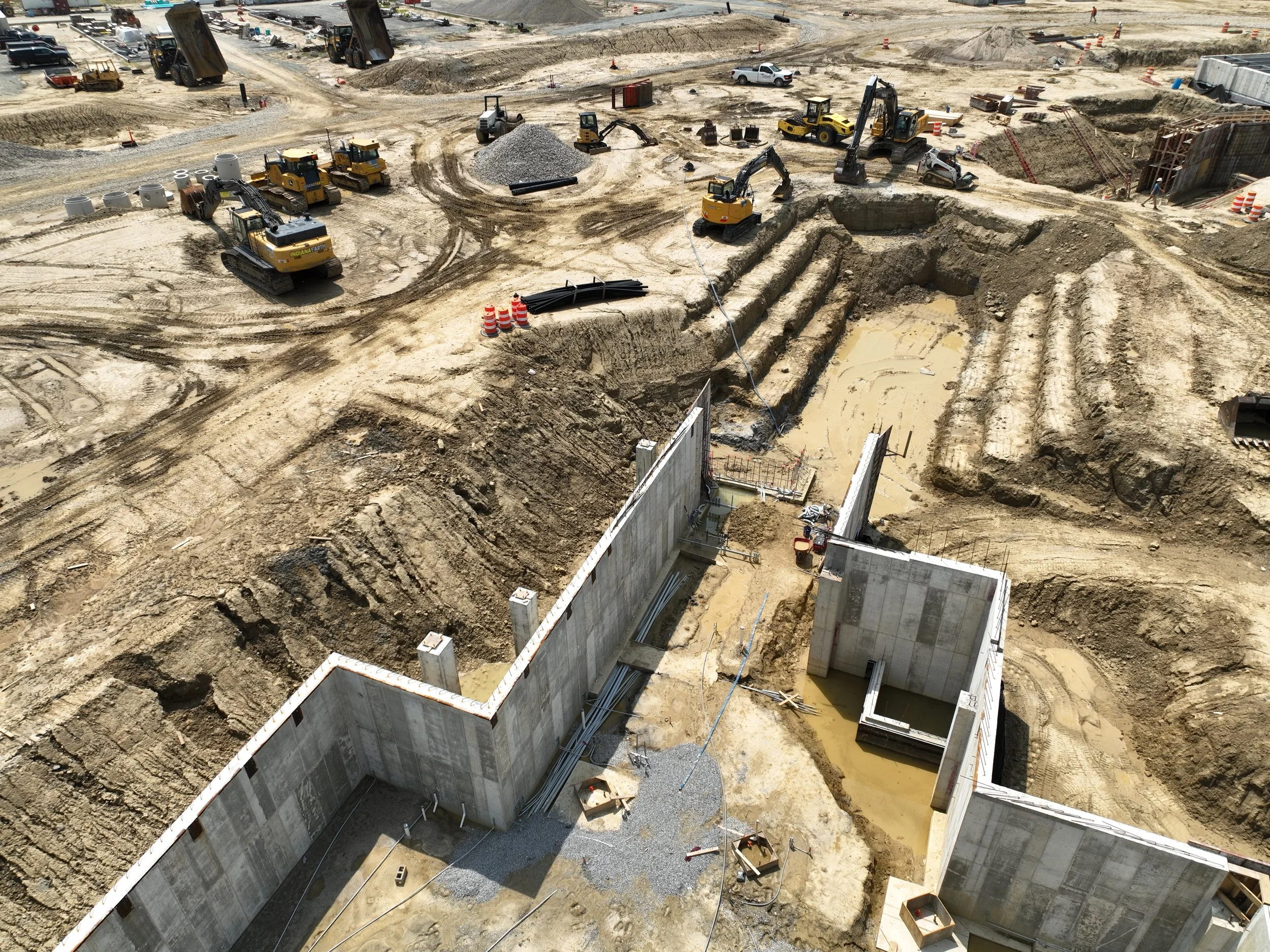 Construction site with concrete walls, heavy machinery, and excavation work in progress.