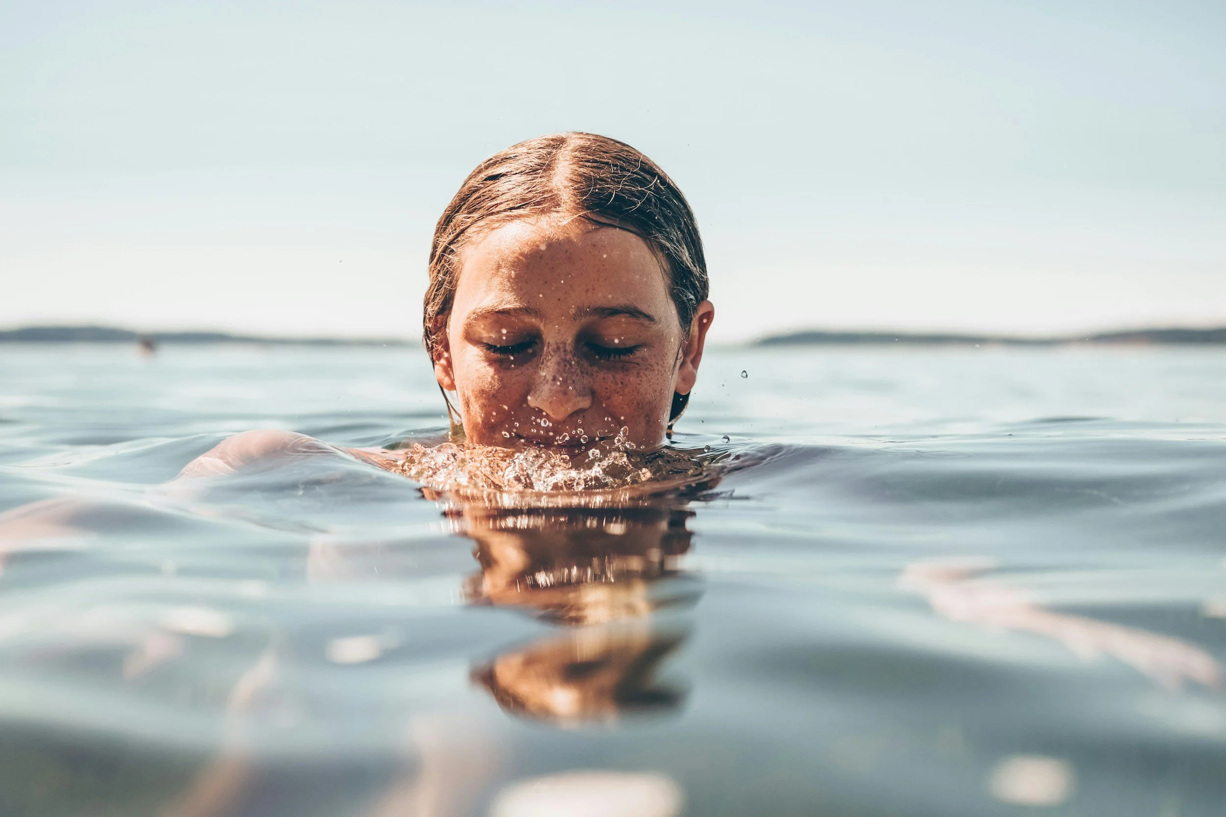 A young girl with wet hair swimming