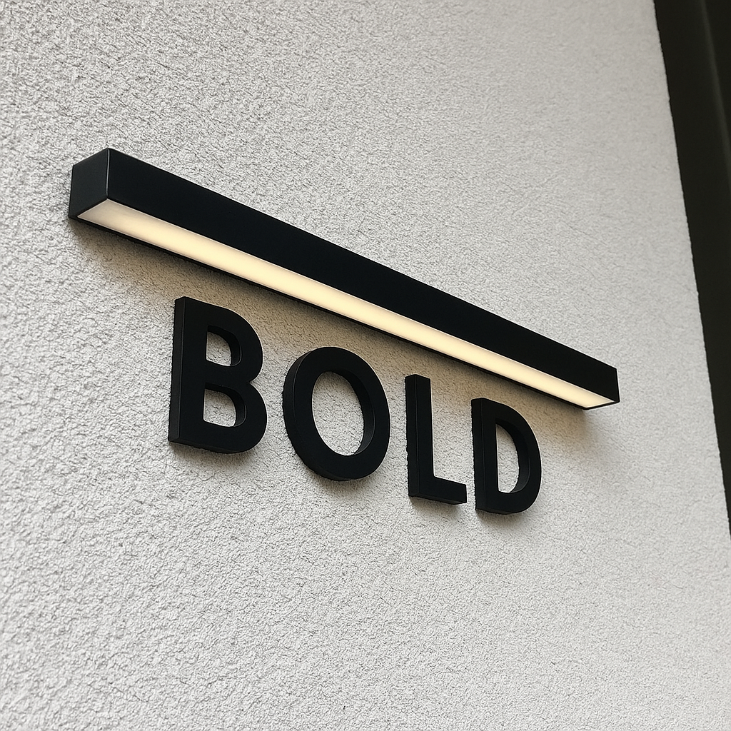 Modern exterior wall sign with the word 'BOLD' in black 3D letters and a horizontal black light fixture above it.
